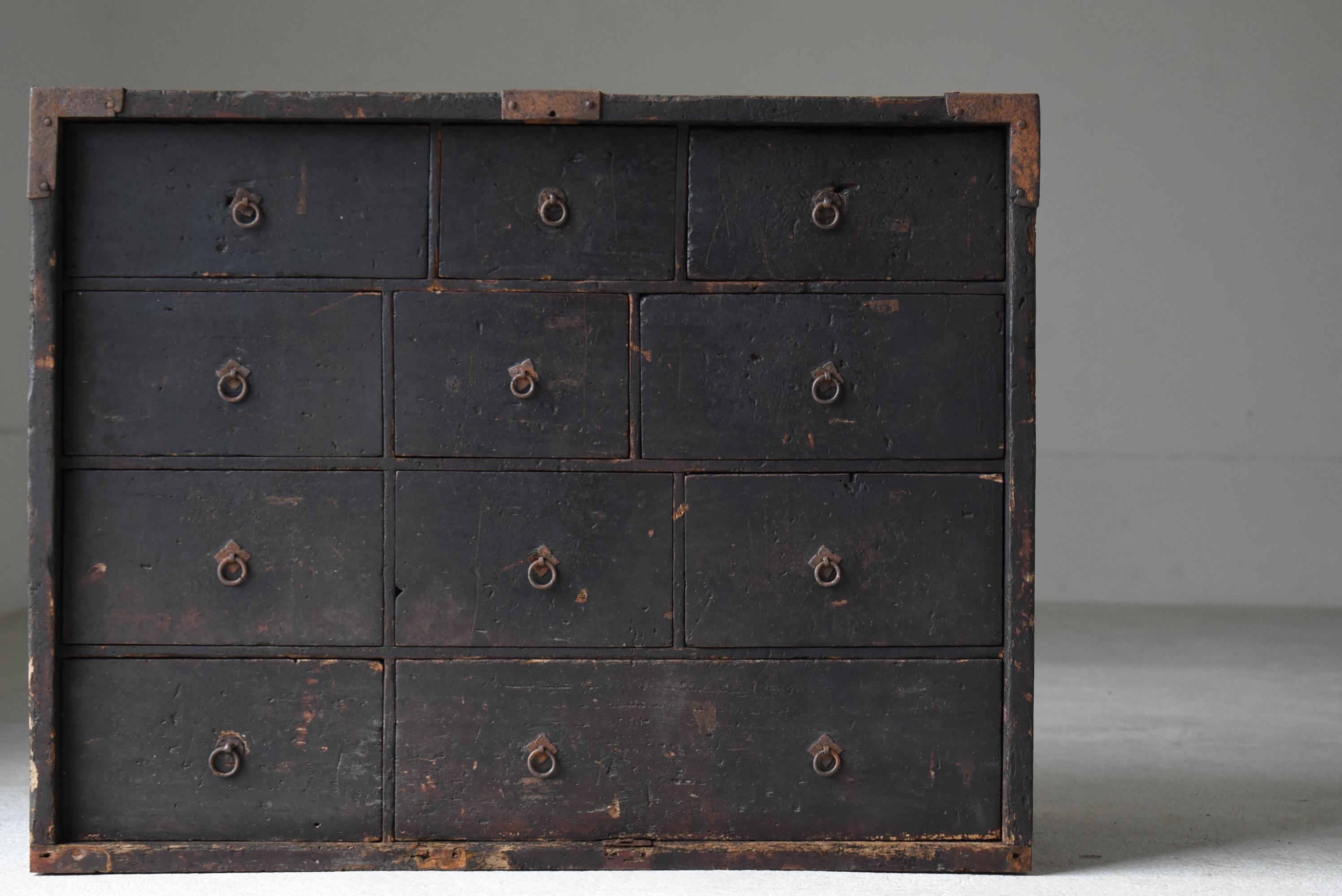 This is a very old Japanese black wooden chest of drawers. The entire piece carries a profound sense of time, as if layers of history have accumulated to form a single, compelling landscape. One of its most remarkable features is the handwritten