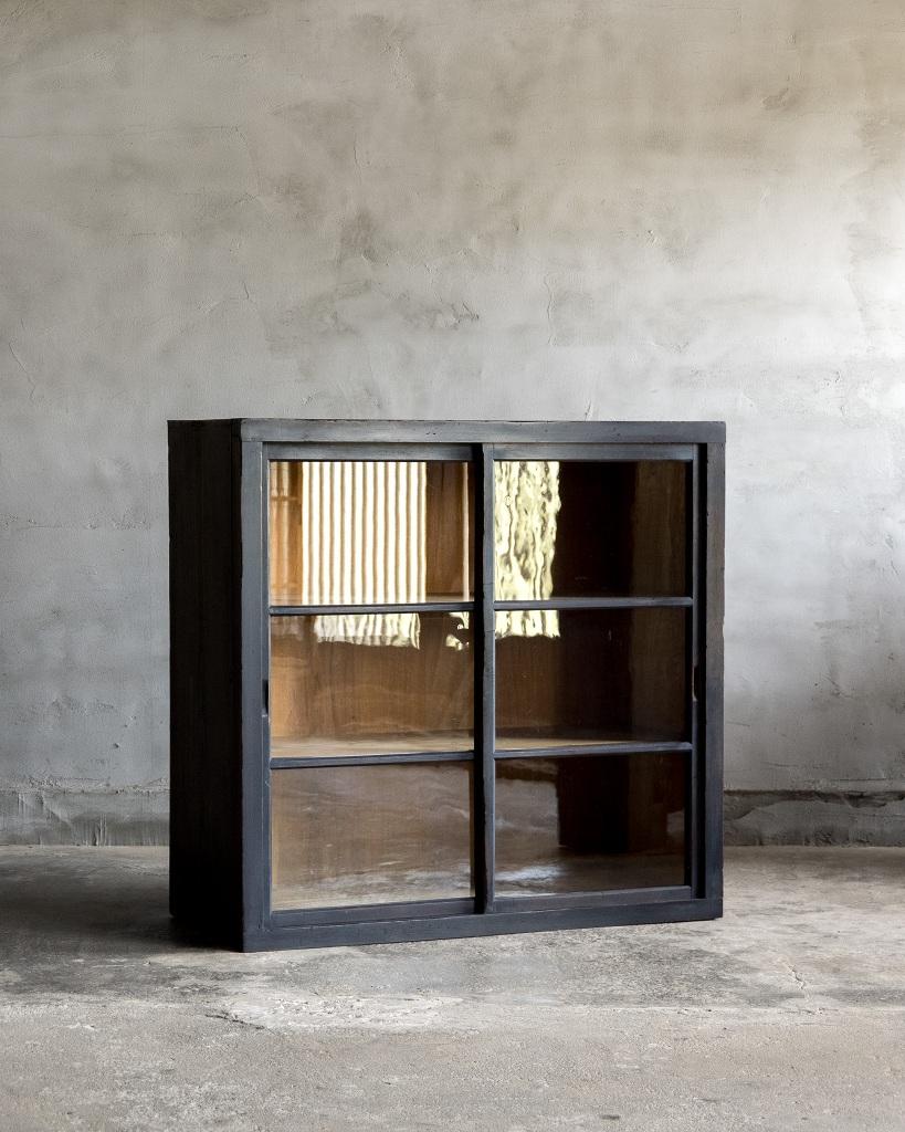 This cabinet was crafted in the Early Showa Period'1926-'.

This antique piece features a striking black finish that adds bold elegance to any room. The glass doors are made from antique glass with noticeable irregularities, giving the cabinet a