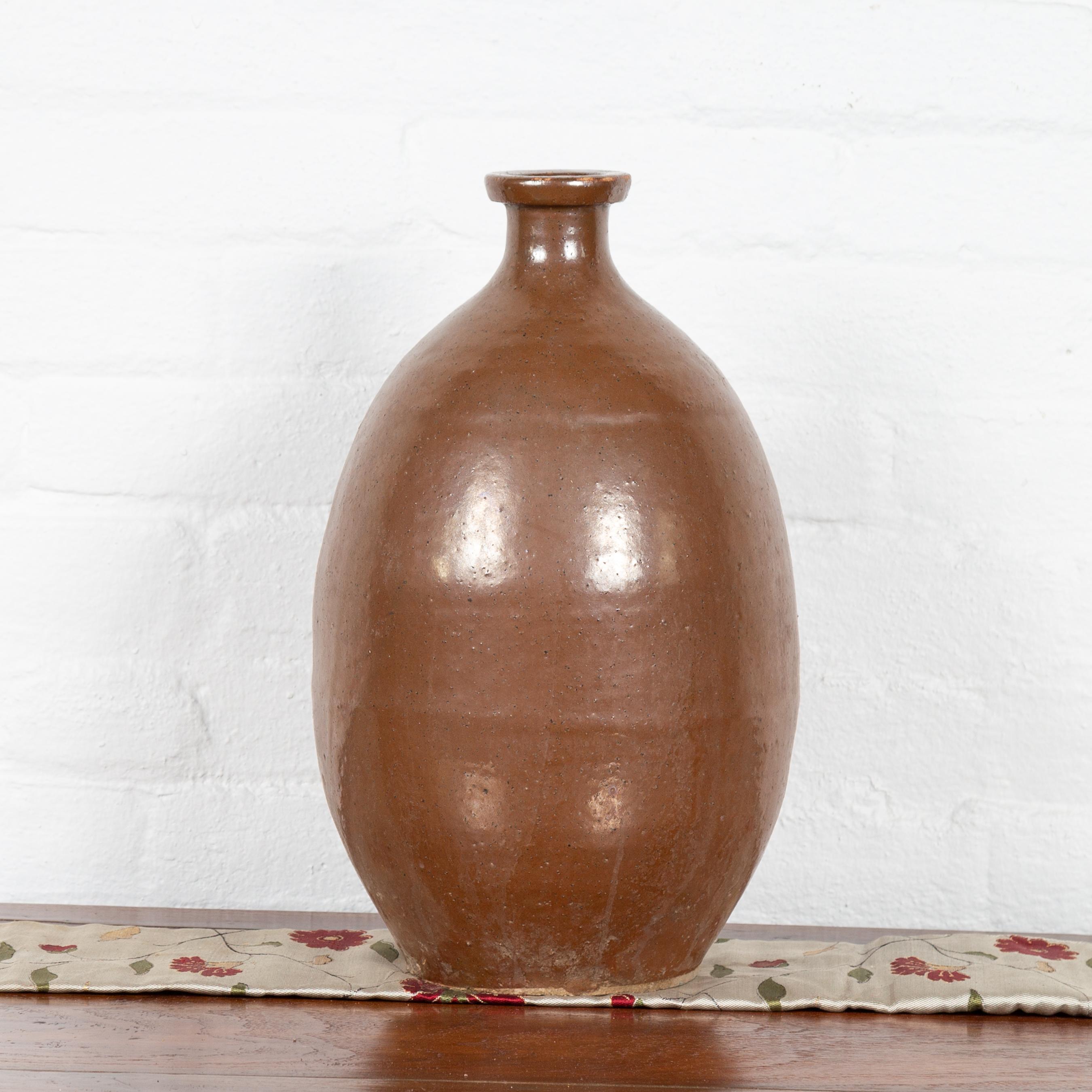 A Japanese brown Tamba Tachikui ware sake jug from the early 20th century. Boasting a lovely brown color with nicely weathered appearance on one side, this Japanese jug was produced in one of Japan’s six famous ancient kilns. Showcasing a circular