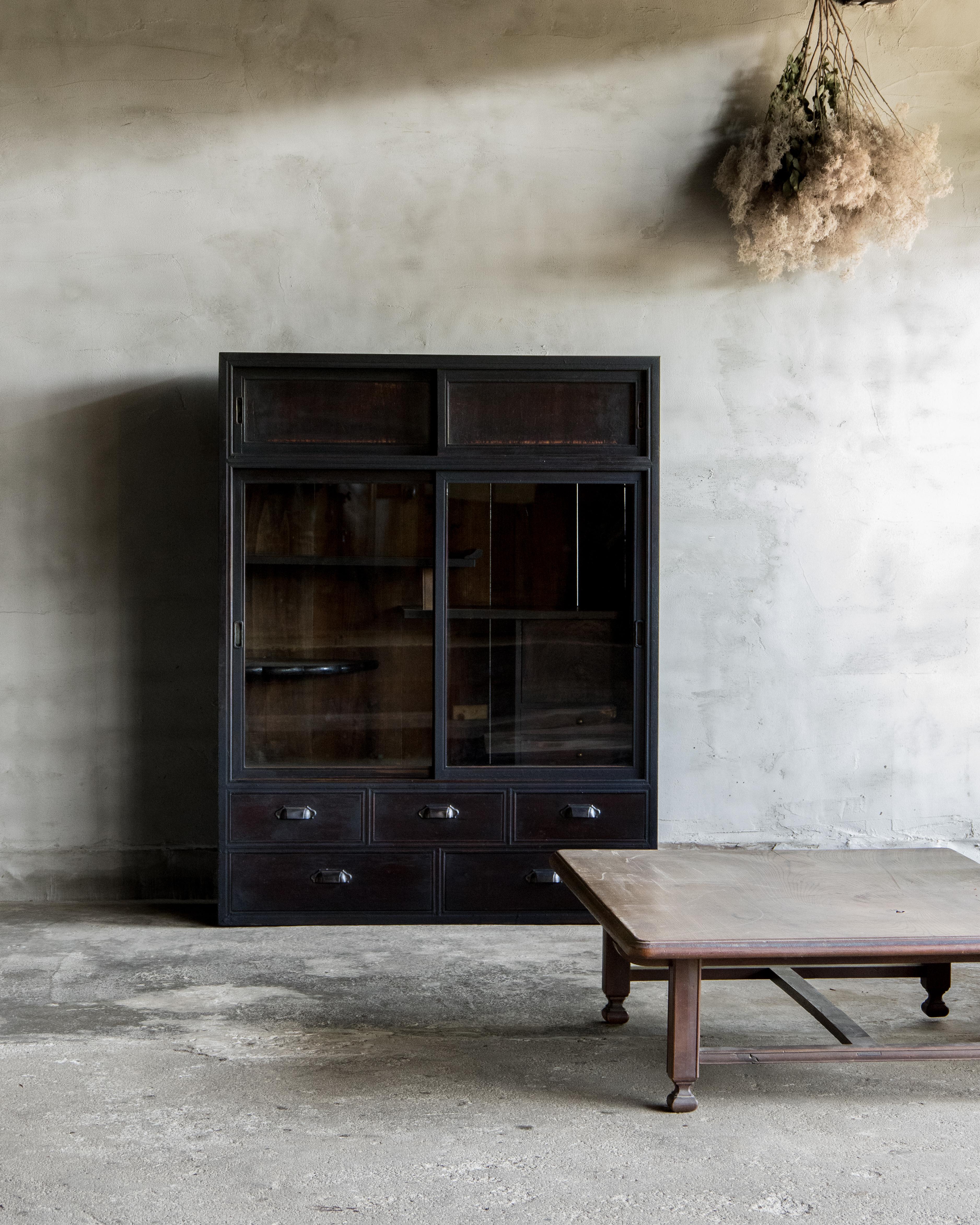 Questo mobile antico con ante scorrevoli in vetro è stato realizzato nell'epoca Taisho (1912-1926).

Costruito in ciliegio e cedro giapponese con frontali dei cassetti in legno di cachi e rifinito con la tradizionale lacca giapponese urushi. Le