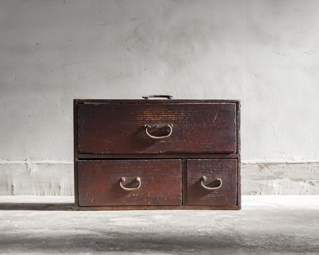 Ce coffre compact a été fabriqué à l'ère Meiji (1868-1912). 

Il est doté d'une poignée sur le dessus, ce qui permet de le transporter ou de le repositionner facilement selon les besoins.

La patine vieillie du bois souligne son charme intemporel,
