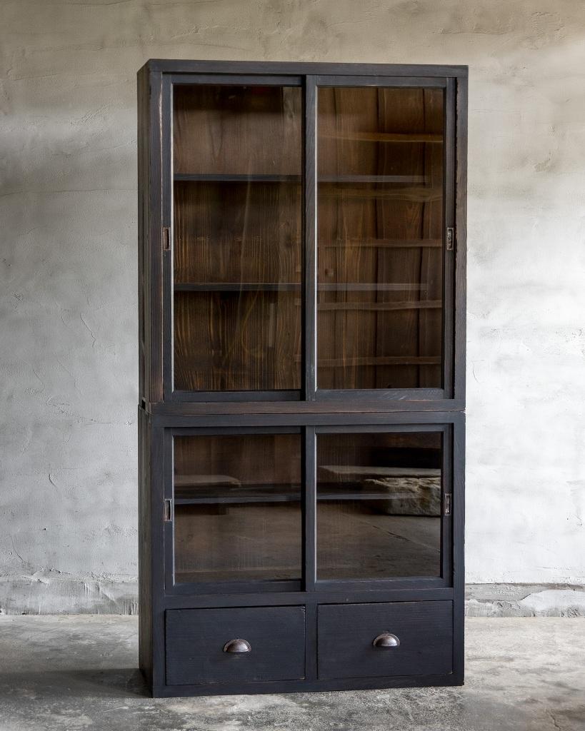 This cupboard was crafted in the Early Showa Period'1926-'.

This antique piece features glass sliding doors that provide easy access and a beautiful display for your items, along with two spacious drawers for convenient storage. It is perfect for