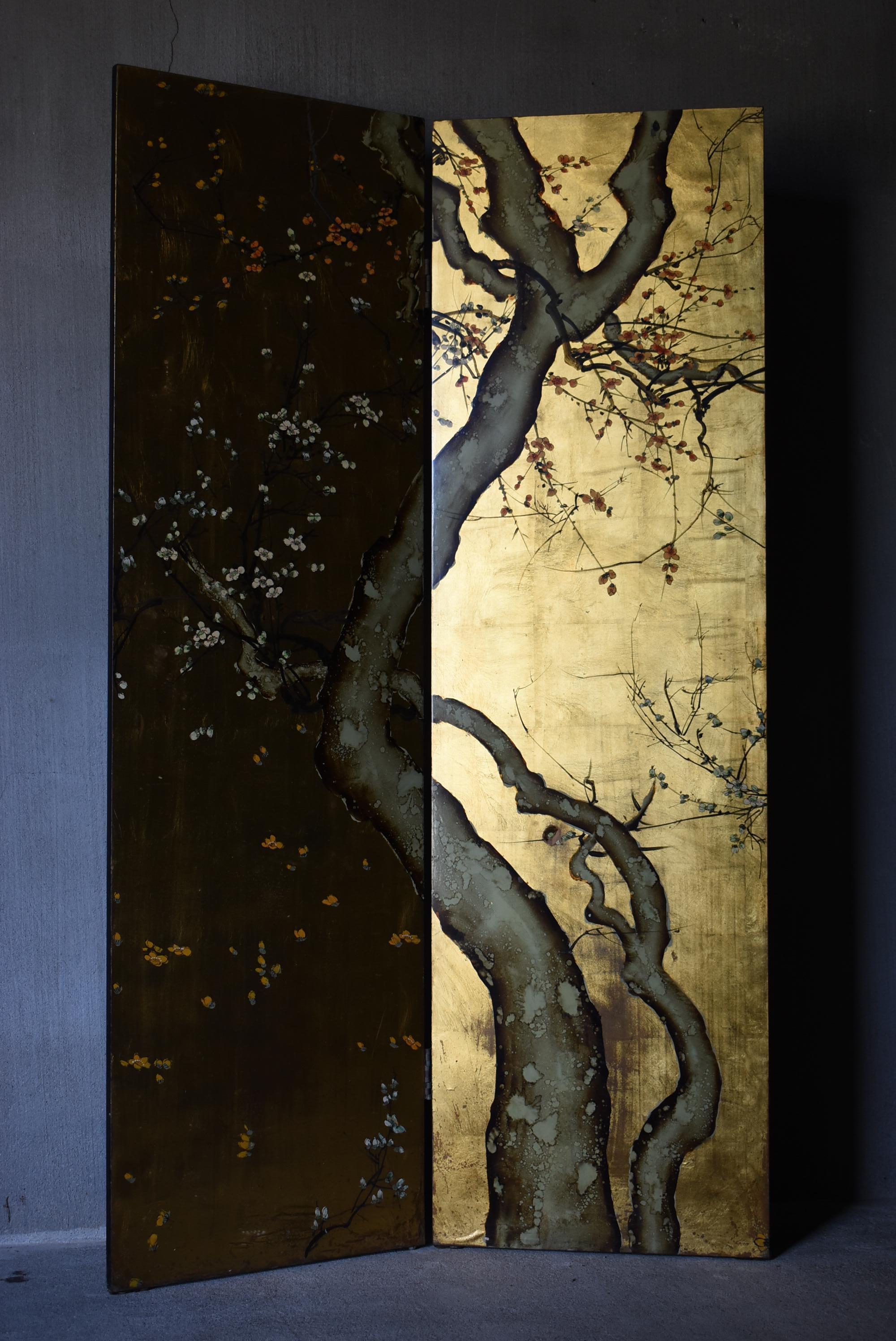 This is a very old folding screen made in Japan.
It is from the early Showa period (1920s-1940s).
It is made of wooden panels with lacquered pictures.

The surface is painted with a plum tree against a golden background.
The reverse side depicts a