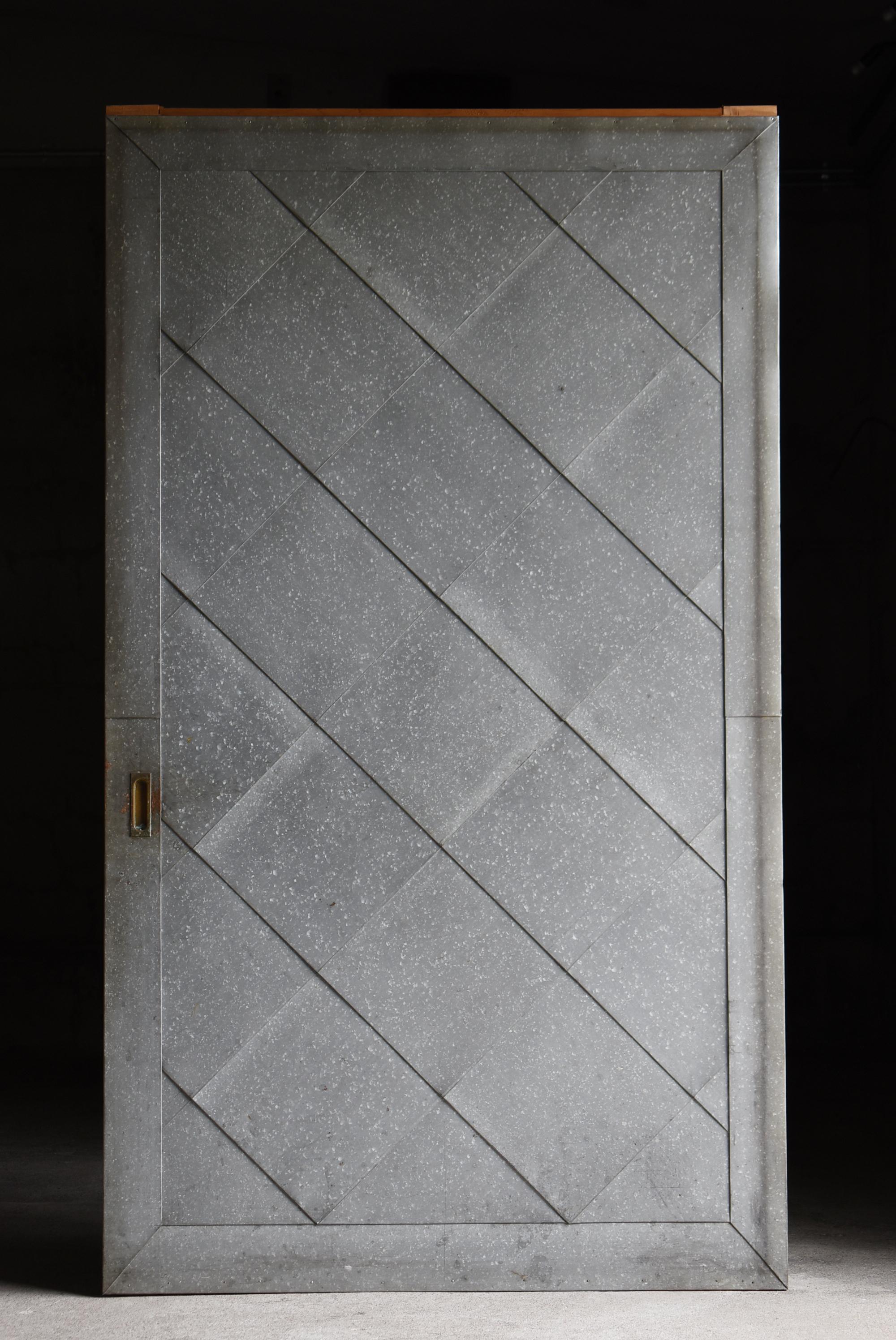 This is an old Japanese sliding door covered with corrugated tin.
It was crafted sometime between the Meiji and Taisho periods (1860s–1920s), and such architectural fixtures have become increasingly rare in modern times.

The wooden frame is made of