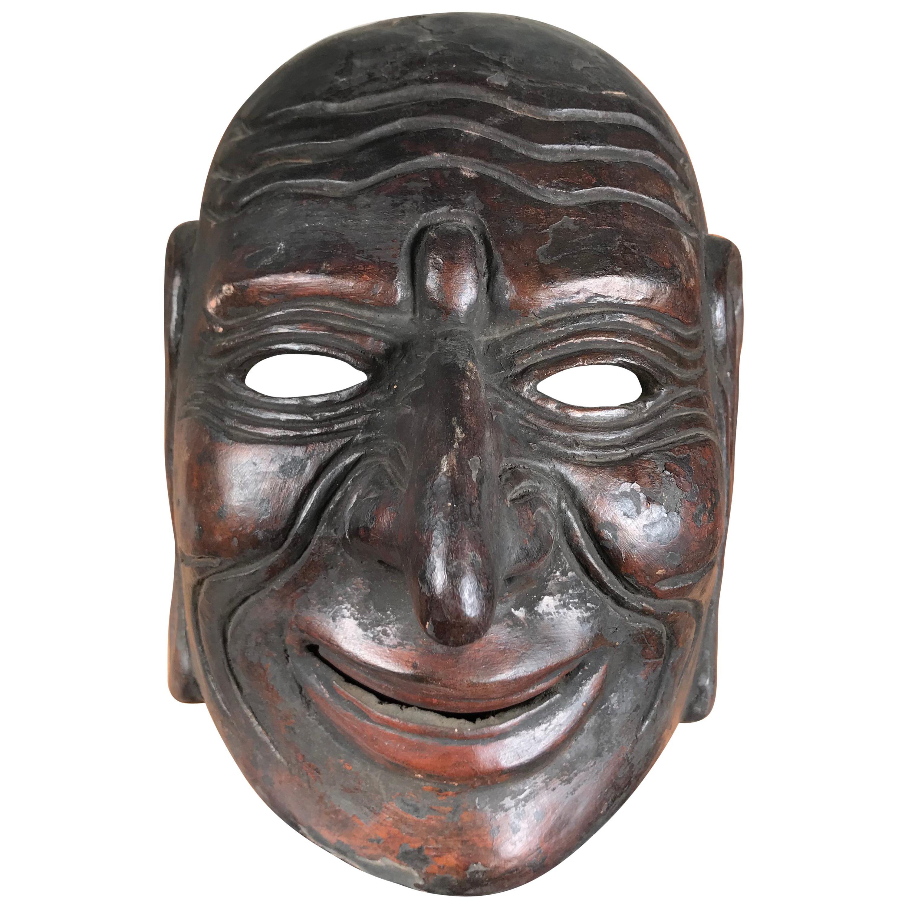 From our recent Japanese acquisitions travels.

This finely carved Japanese antique wooden theater mask is a superb example of this character with its dramatic brow and pleasant joyful ear to ear smile. This mask and character may be seen in