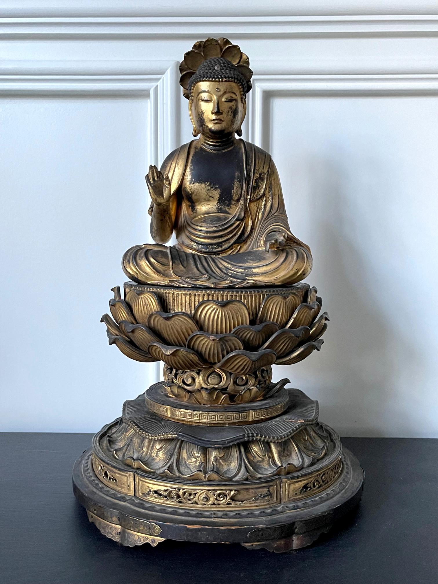 A Japanese carved wood Amitabha (Amida) Buddha statue with residual gold leafed surface circa 19th century (late Edo period). The buddha is seated in the padmasana position on an elevated double lotus throne, under a small lotus halo canopy. His