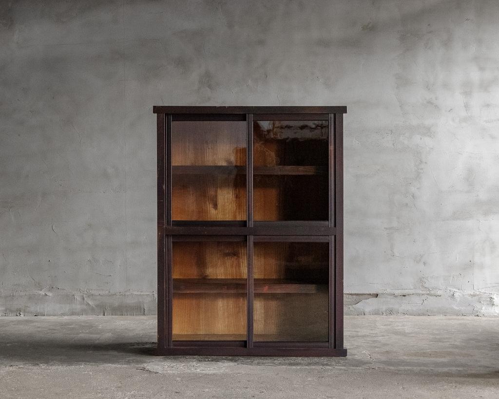 Se trata de una vitrina fabricada en la época Taisho (1912-1926).

Presenta un cristal antiguo con una distintiva textura ondulada, característica de su época, que añade calidez y encanto a su aspecto general. El marco de las puertas de cristal está