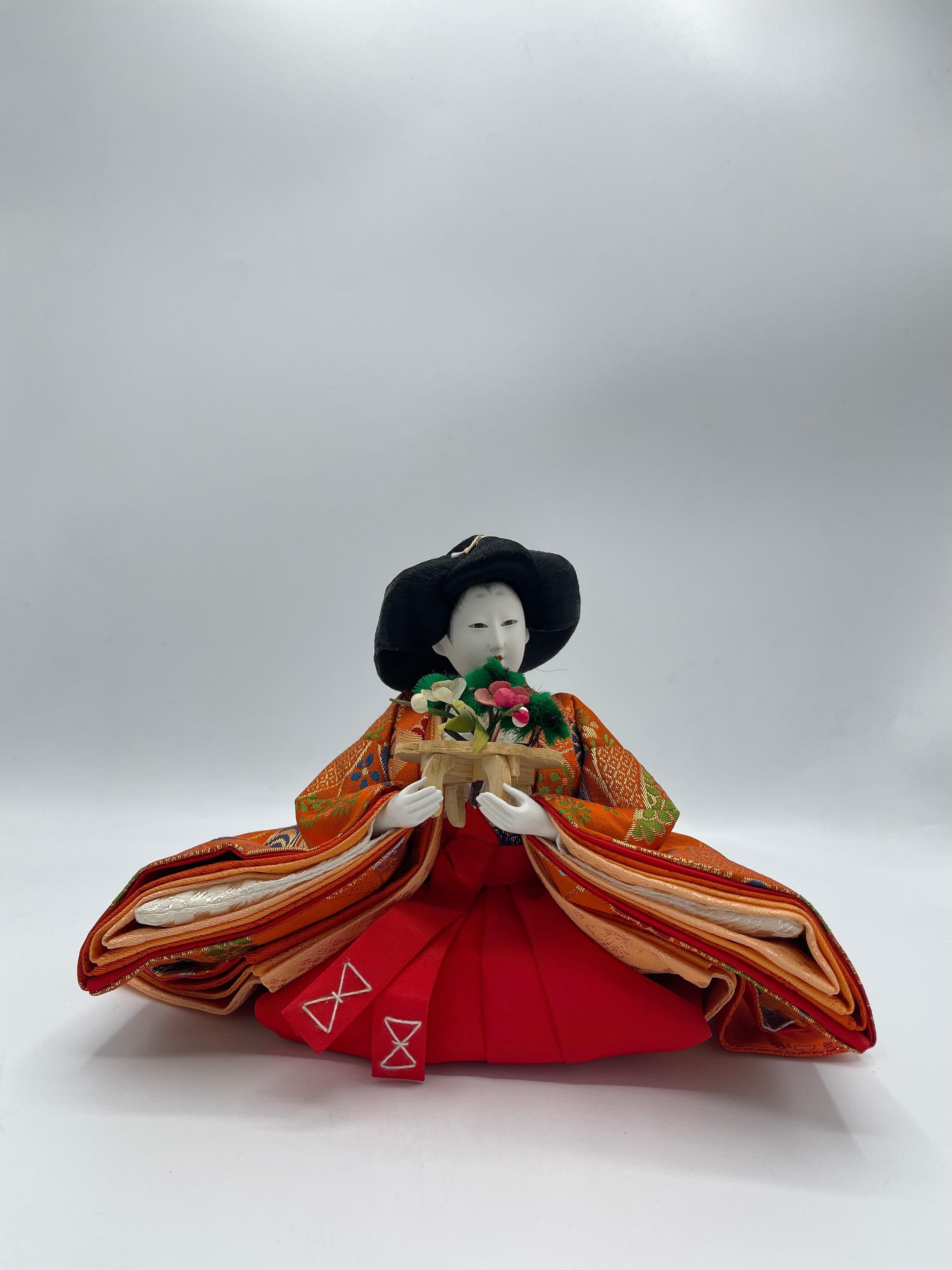 Il s'agit d'une poupée que nous utilisons pour le jour de Hinamatsuri. Cette personne est l'un des Sannin Kanjo, appelé Sanpo.
Cette personne a une fleur. Cette poupée a été fabriquée avec du plastique, du coton, de la soie, du bois et du métal.