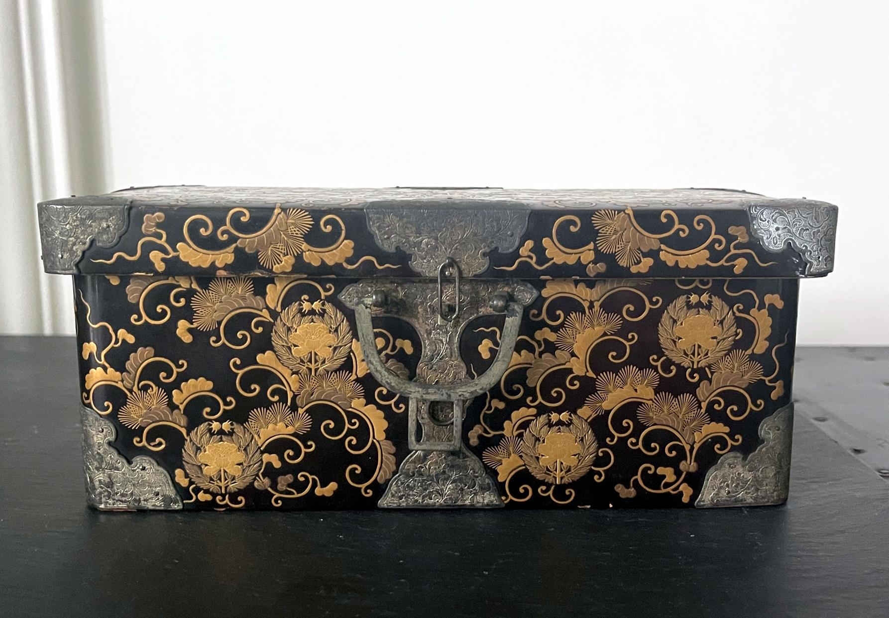 A Japanese lacquered box with lid in the shape of a miniature Hasami-Bako (traveling chest) circa late 18 to early 19th century of the Edo period. The black box is decorated with fine golden hiramaki-e painting of scrolling vines, pine needles and