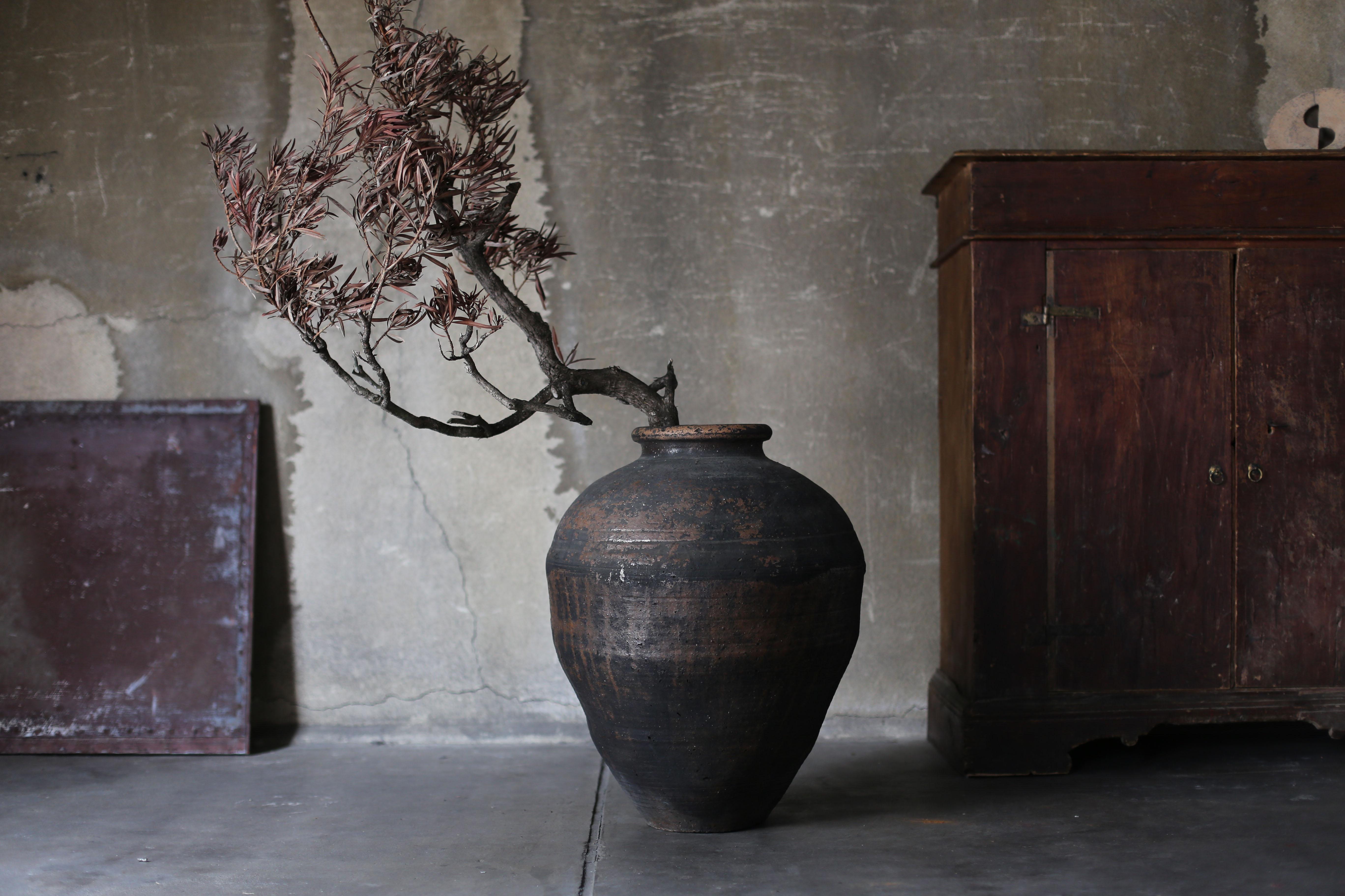 This large ceramic vase was made in Mashiko, Japan. Mashiko is a traditional and famous region for pottery.
It dates from the Meiji period (1860s-1900s).

It is generally black in color, but has a small amount of brown glaze.

Depending on the angle