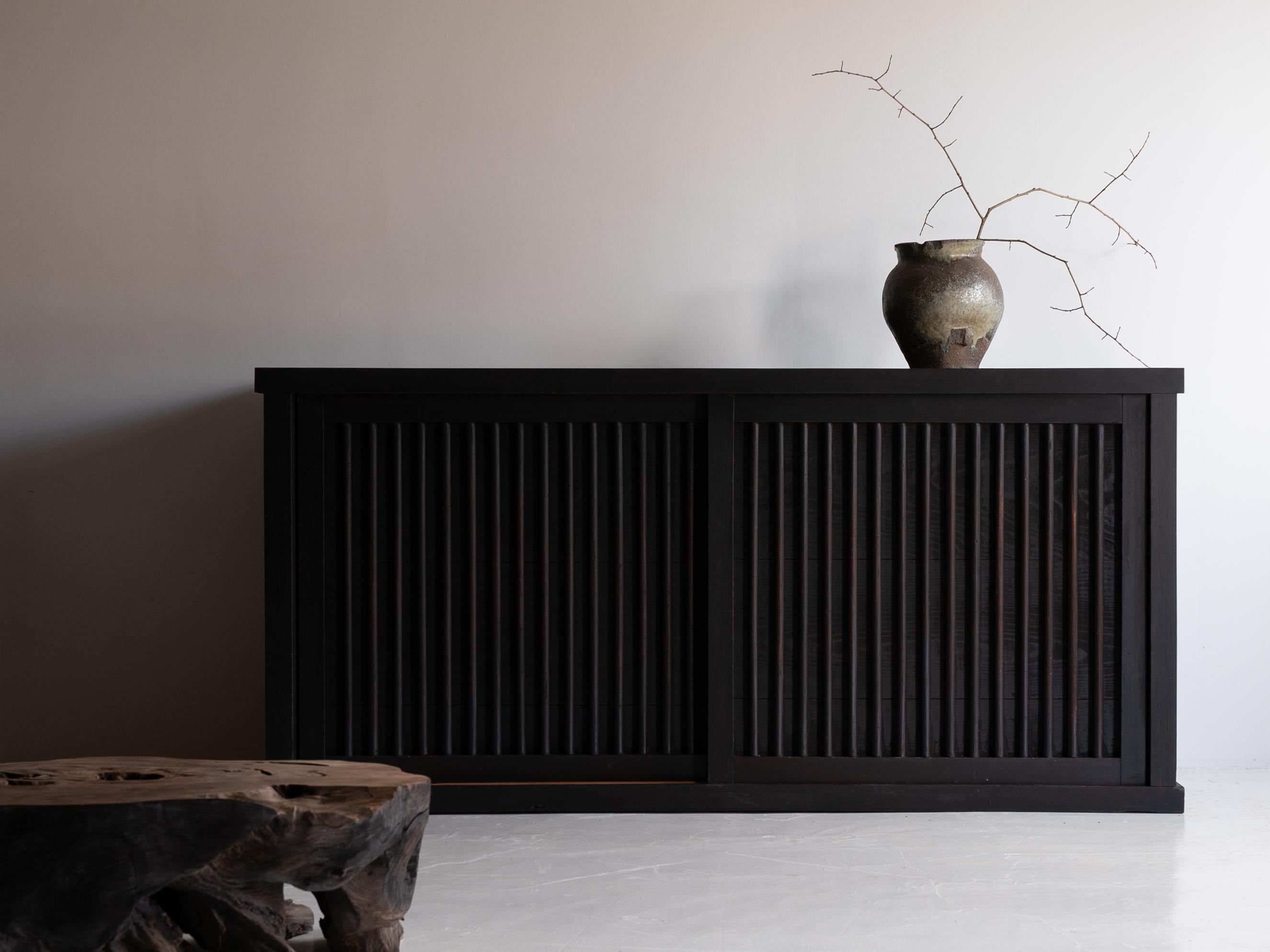 Il s'agit d'un tansu (coffre) japonais historiquement significatif de l'ère Meiji (années 1860-1900), fabriqué en bois de cèdre.

Son design minimaliste et raffiné incarne l'esthétique japonaise traditionnelle. Les portes coulissantes en treillis