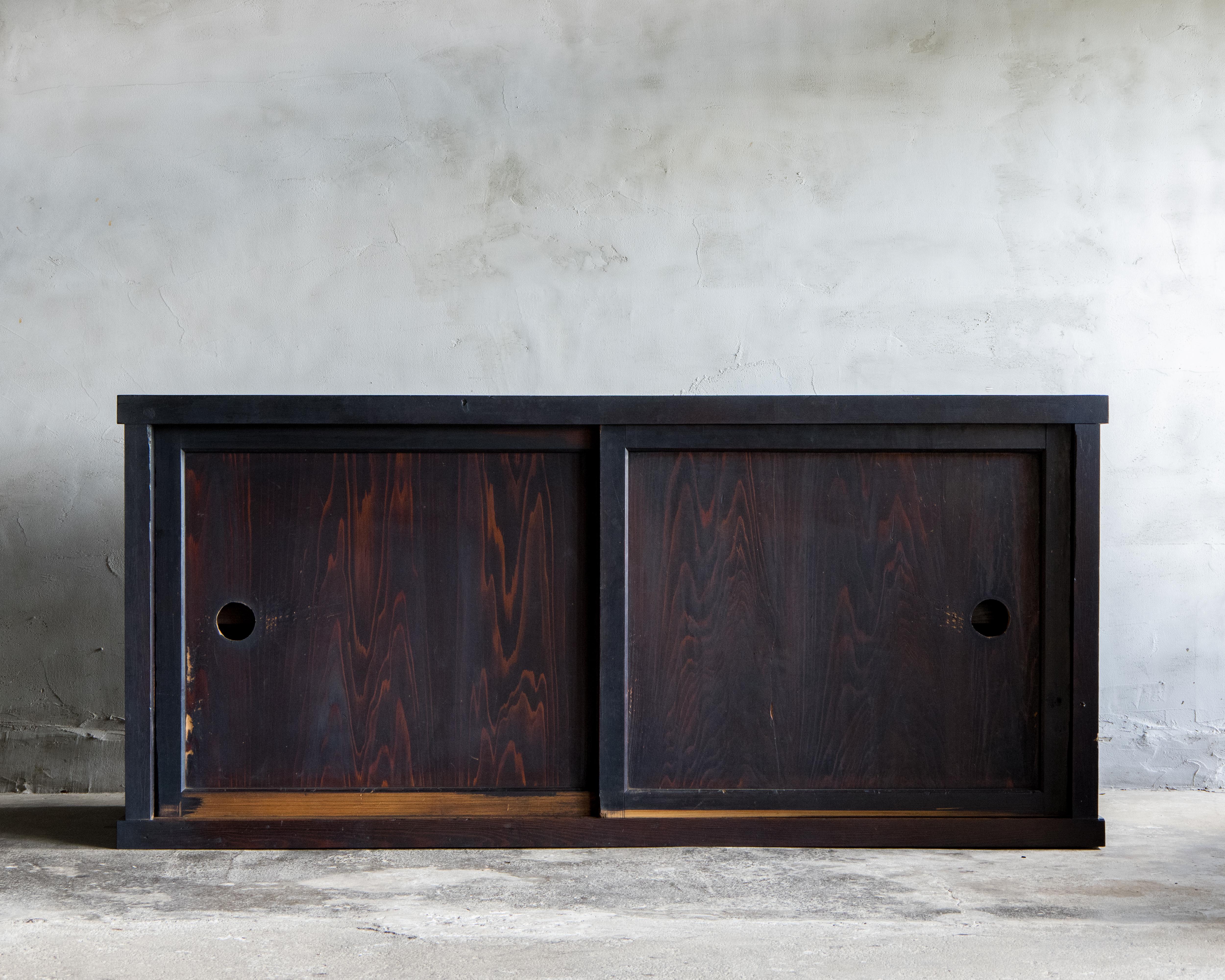 Questo antico Mizuya Tansu di grandi dimensioni è stato realizzato in epoca Meiji (1868-1912).

Le sue semplici ante scorrevoli e la finitura scura e consumata dal tempo riflettono la tranquilla bellezza del wabi-sabi. La superficie era