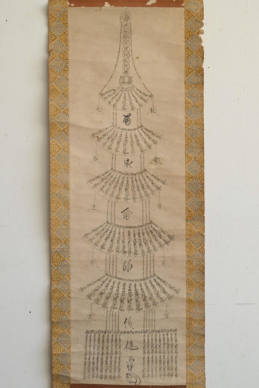 This is a slightly different Buddhist painting believed to have been created by a Japanese temple monk during the Edo period (late 17th to 19th century). Rendered in ink on paper, the artwork forms the shape of a pagoda composed entirely of the six