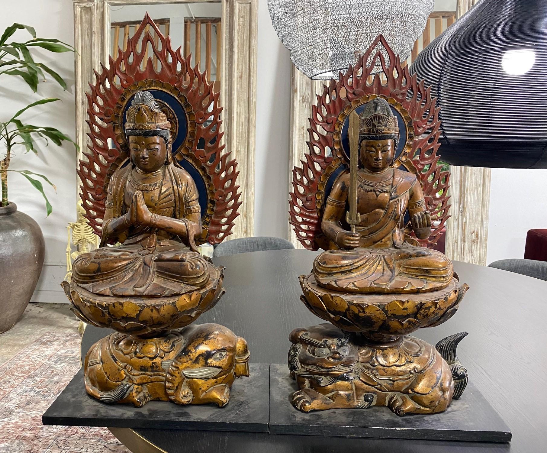 Coppia di statue/sculture di buddha giapponesi in legno intagliate a mano che siedono serenamente in cima ai loro troni di petali di loto. Gli intricati dettagli intagliati e i colori meravigliosamente vivaci (soprattutto nelle aureole a forma di