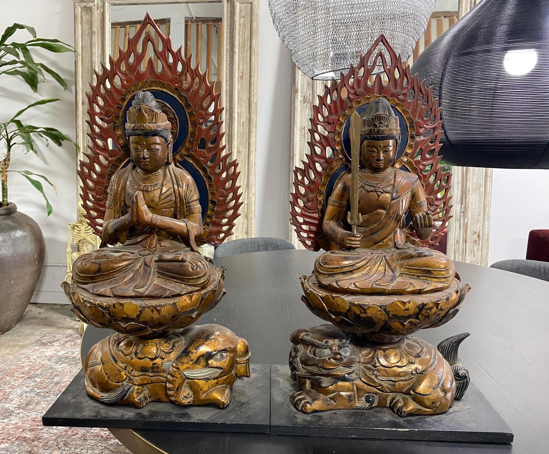 Truly stunning pair of hand-carved wood Japanese buddha statues / sculptures that sit serenely atop their lotus petal thrones. The intricately carved details and wonderfully vivid coloring (especially on the flame-like halos) make this pair quite