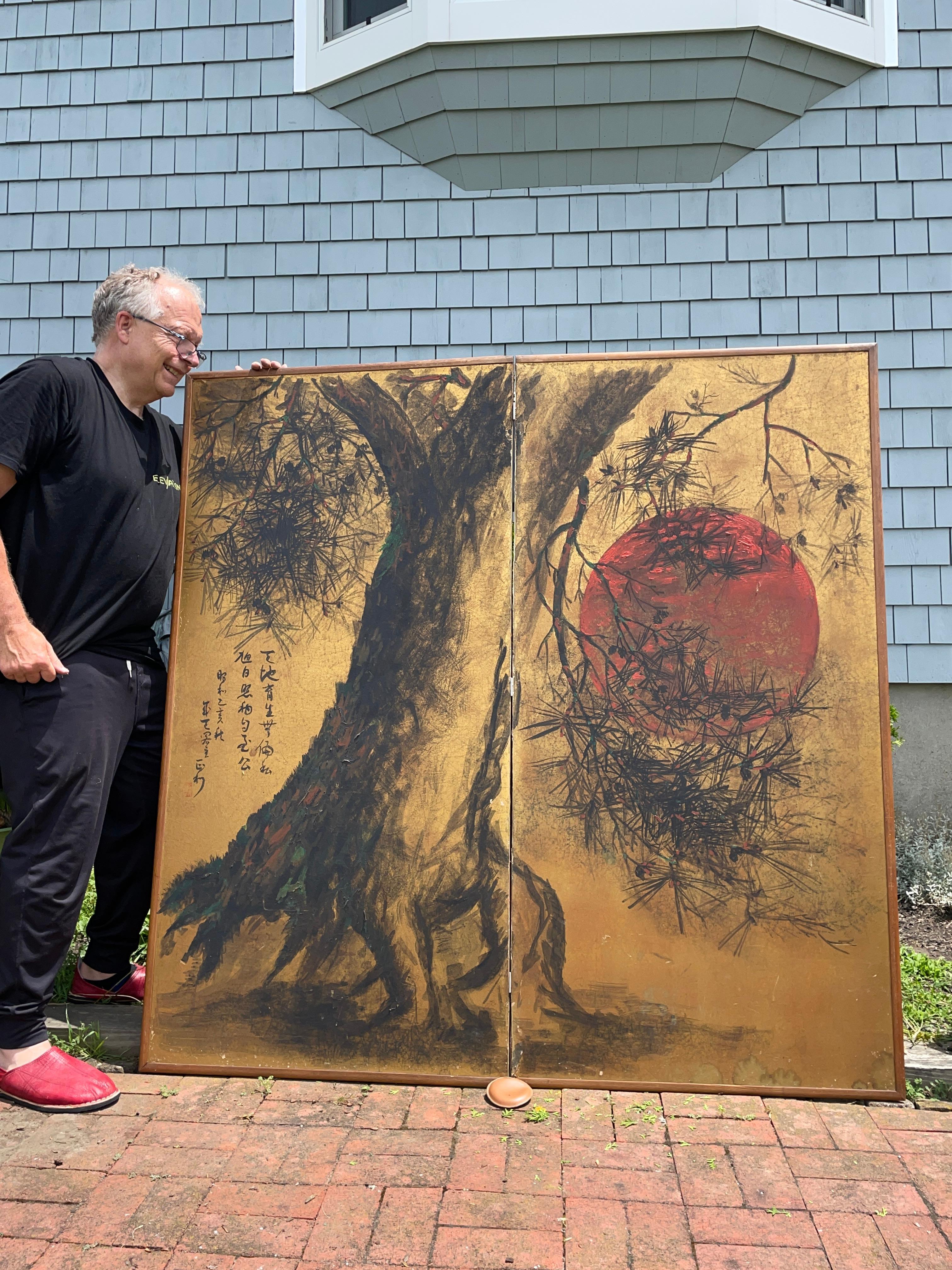 A rare depiction of a brilliant red moon shadowed by a single pine tree - a Japanese antique hand painted two-panel folding screen byobu form artistically conceived in primary red andblack colors on a gold ground and in a medium scale size.
