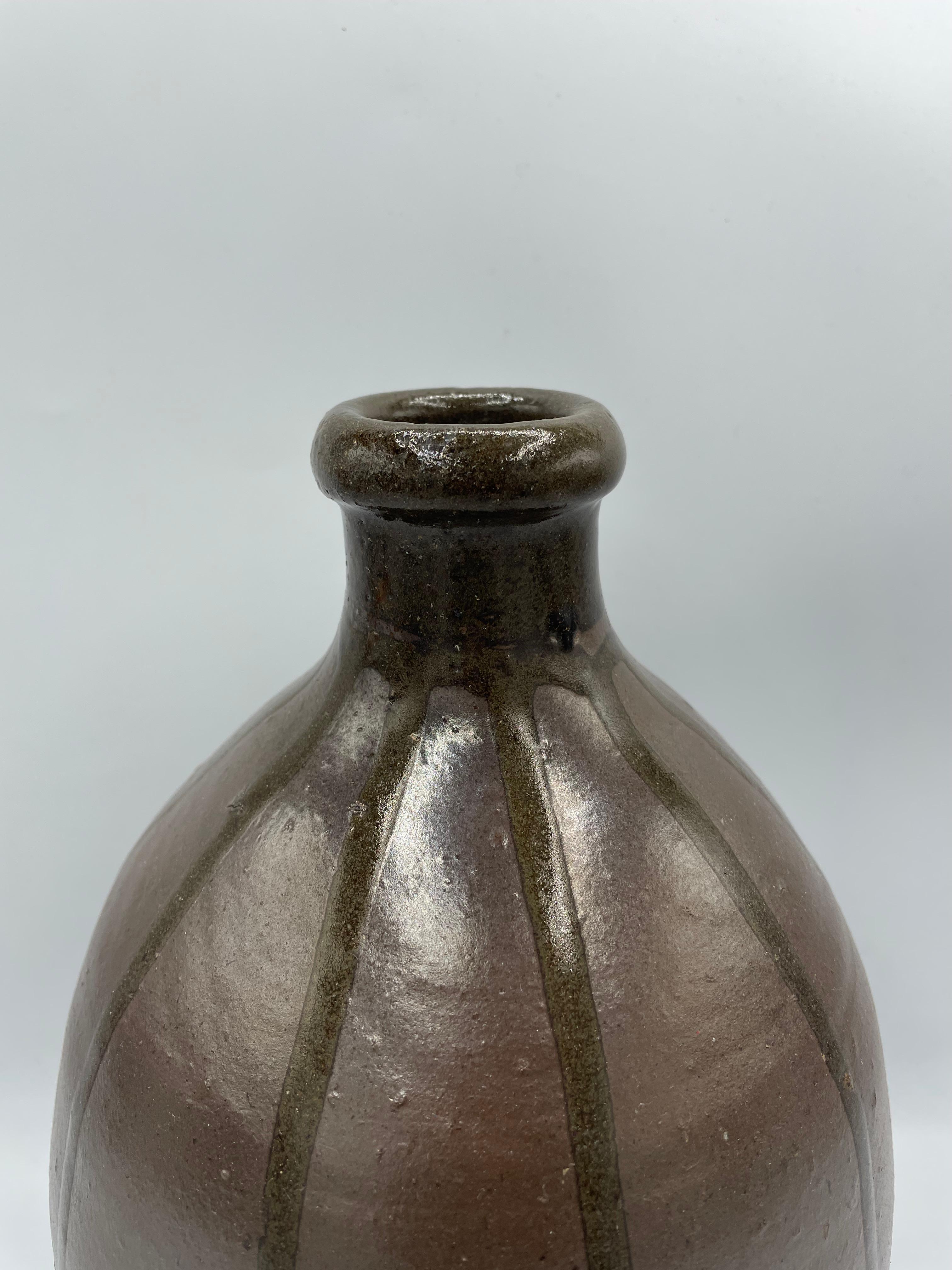 This is a sake bottle which was made around 1900s in Meiji era.
These kind of bottles are called Kayoi tokkuri or Binbo tokkuri.
It can be used as a sake bottle but also as a flower vase.

It is thought to have been distributed from the late Edo