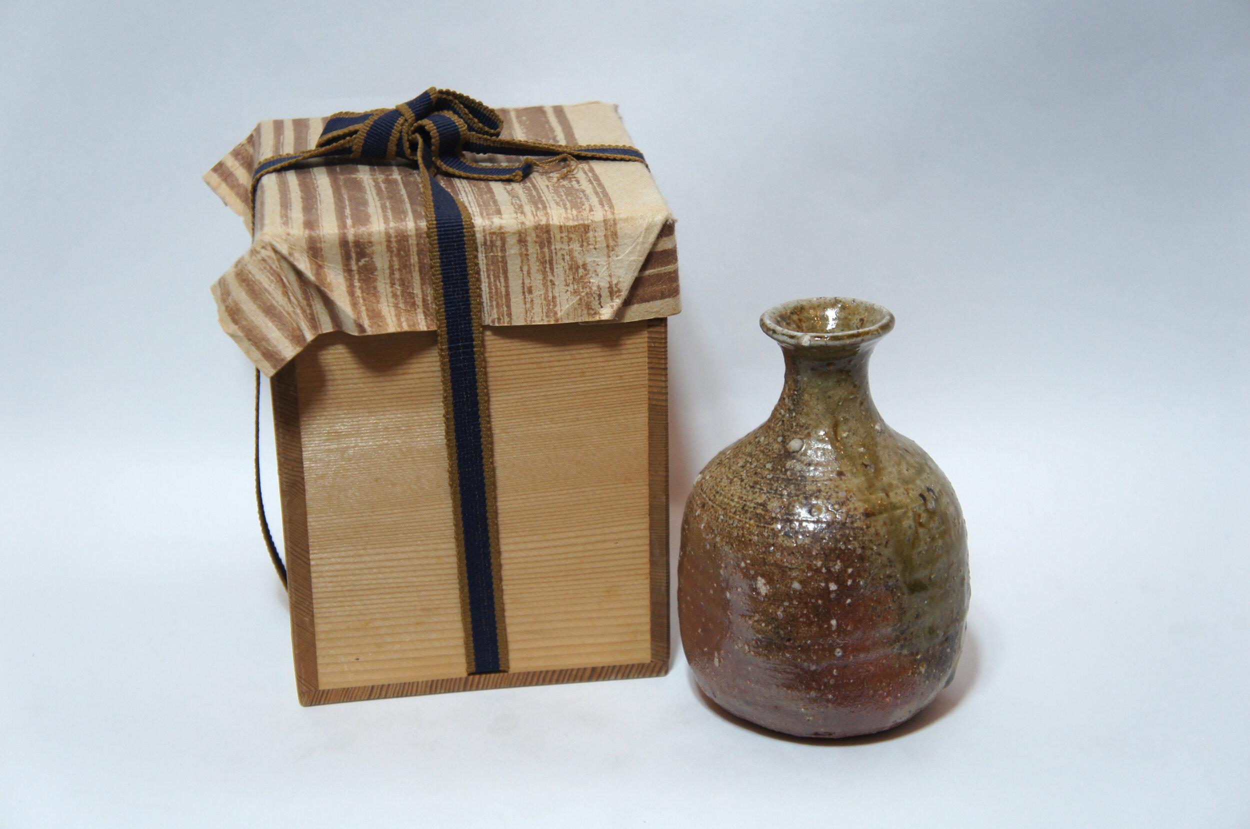 This is a bottle of sake 'Tokkuri' which was made with Shigaraki style (Shigaraki ware).
It was made around 1930s in Showa era and it is made with porcelain.

Dimensions: 8.5 × 9 × H13 cm

Shigaraki ware is a type of stoneware pottery made in