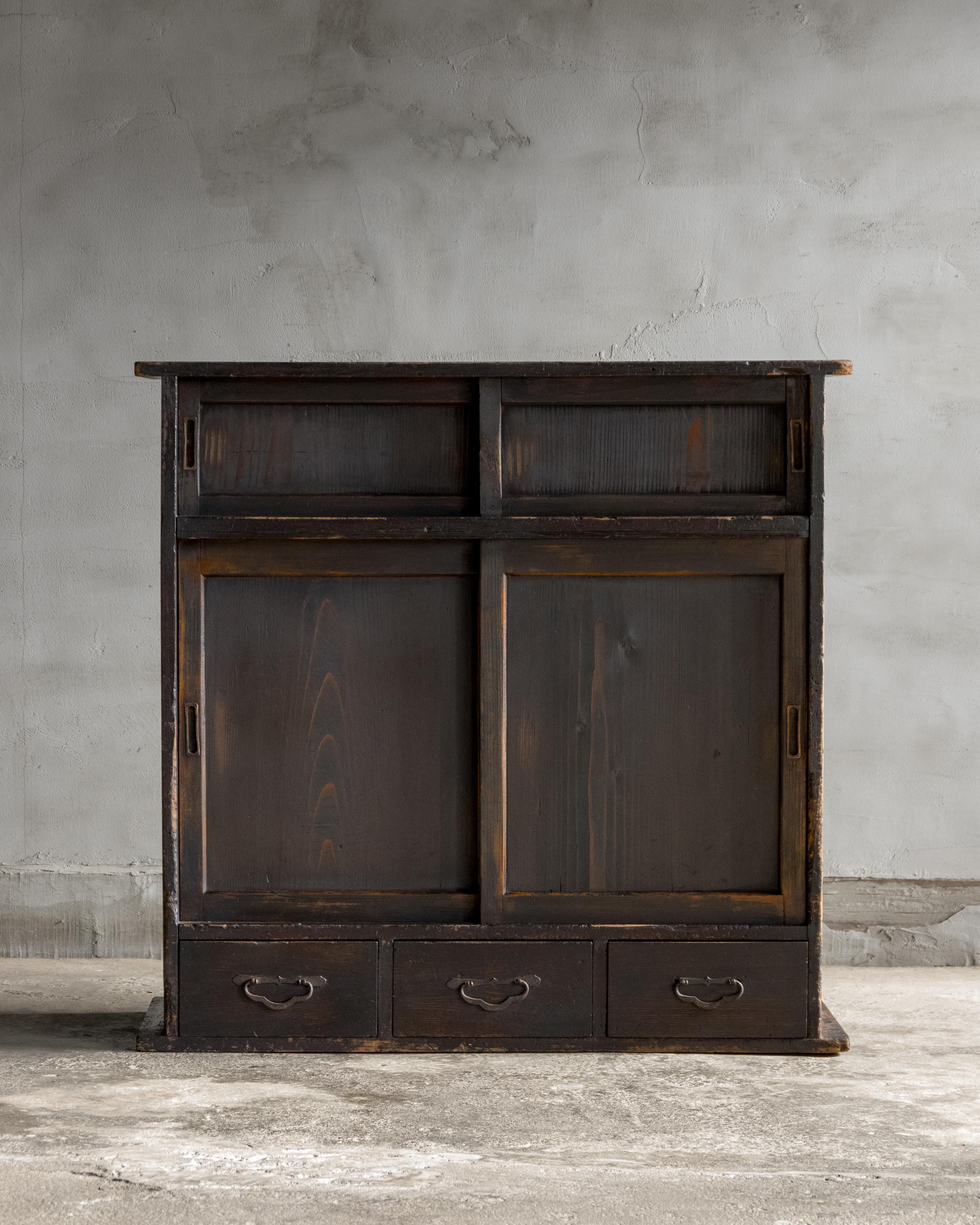 Questo mobile giapponese ad ante scorrevoli (cha tansu) è stato realizzato durante il periodo Taisho (1912-1926) utilizzando una sapiente combinazione di legni: kiri (paulownia) per la struttura, sugi (cedro giapponese) per i pannelli delle ante e