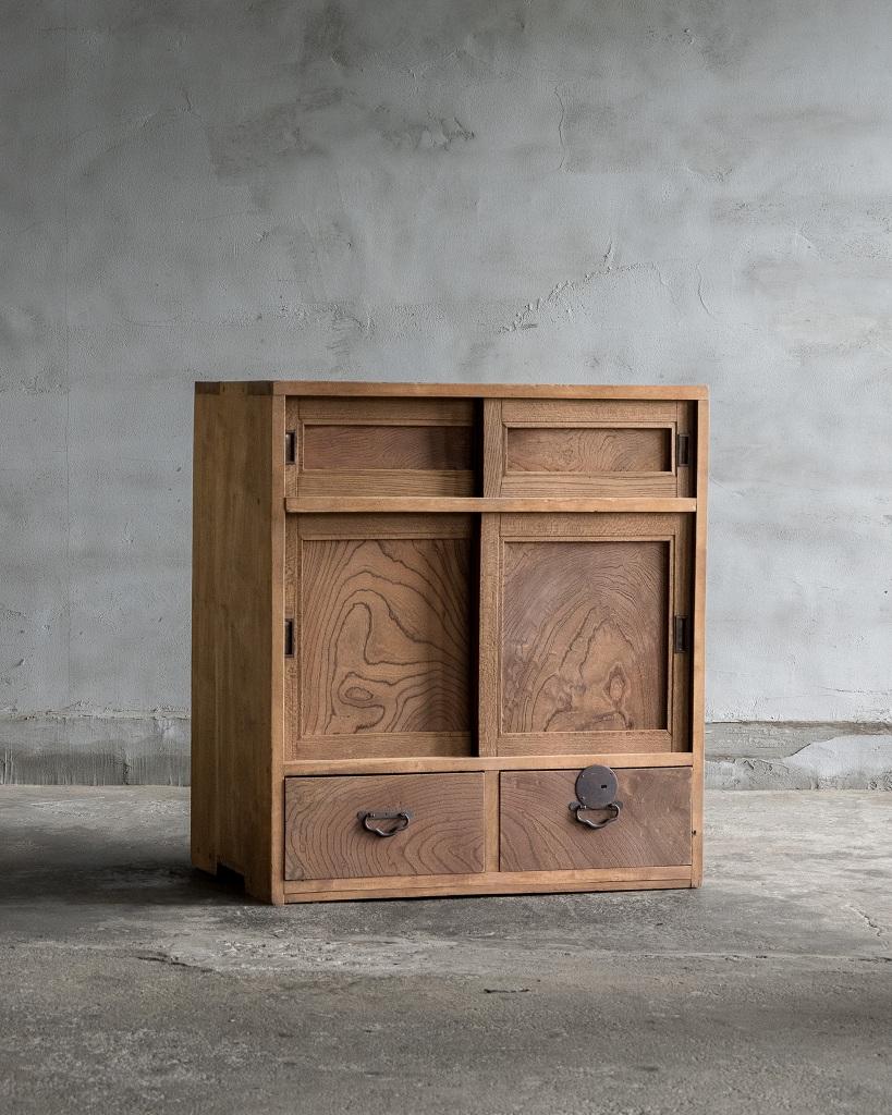 Questo piccolo mobile antico è stato realizzato nell'epoca Taisho (1912-1926) e riflette l'eccezionale maestria dell'epoca. Il pannello frontale è realizzato in squisito legno di keyaki, con il suo sorprendente motivo a venature che lo