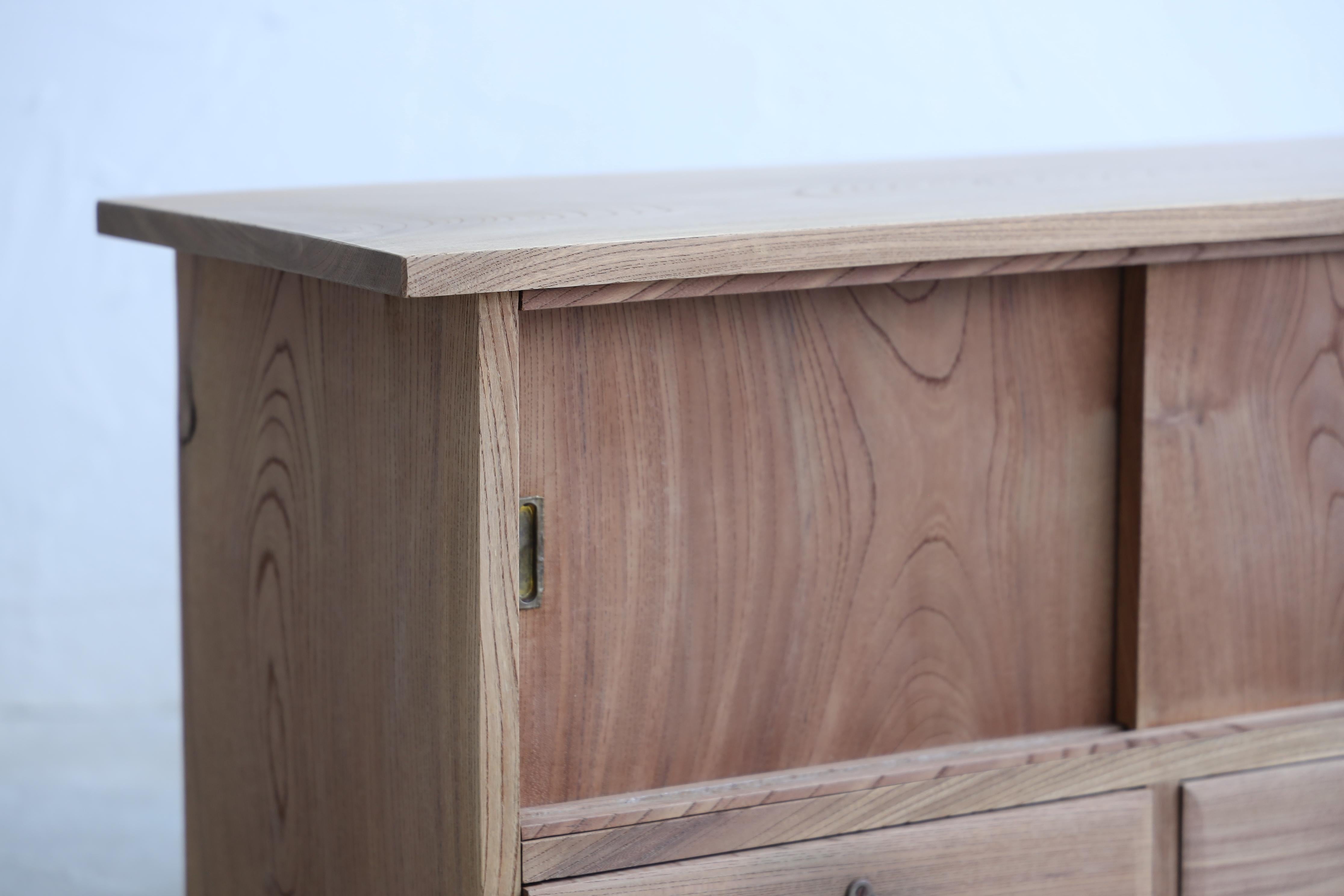This small yet striking storage shelf is made from high-quality keyaki wood.
This is an antique from the Taisho period.

It is just the right size to place next to a low sofa, and is made from a single piece of keyaki wood not only for the top but