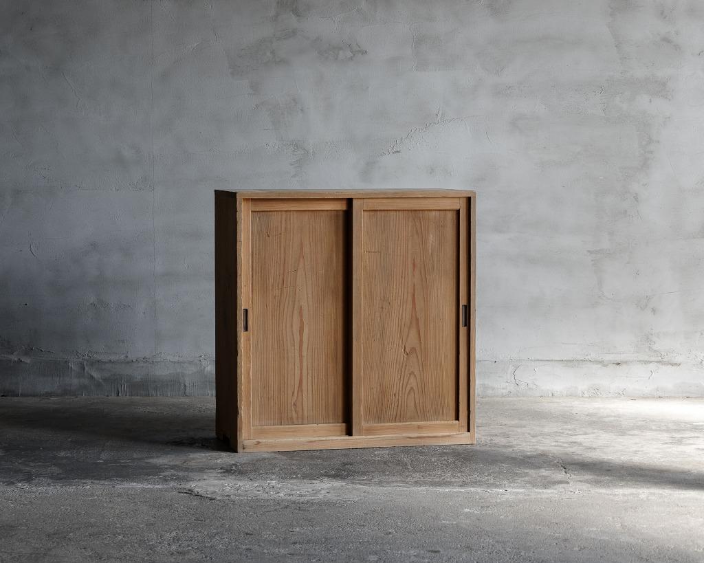 This is a Japanese antique small sliding door cabinet.
It was made in the Taisho Era(1912-1926).

This charming antique small cabinet from Japan is crafted with natural cedar wood, showcasing its authentic texture and warmth. Its design is simple