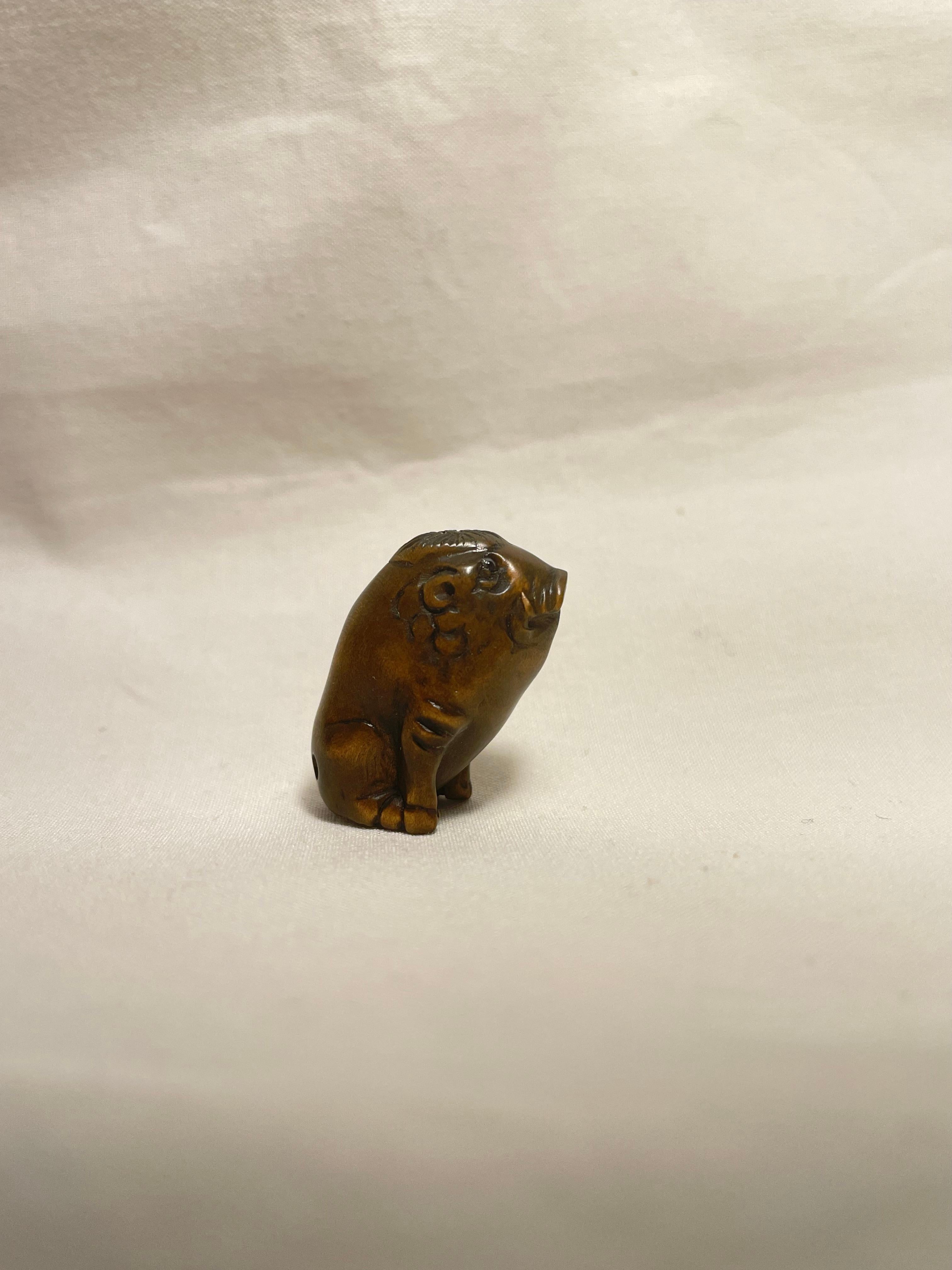 This is an antique netsuke made in Japan around Showa period 1960s.

Dimensions: 1.5 x 2.3 x H2.5cm
Sculpture: Wild Boar
Era: 1960s (Showa) 

Netsuke is a miniature sculpture, originating in 17th century Japan.
Initially a simply-carved button
