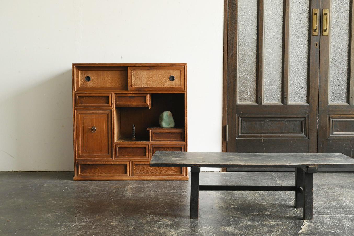 This compact yet finely crafted piece of furniture was made in Japan in the early 20th century. Likely constructed from aged cedar or cypress, the wood has developed a rich patina over time. Its simple, refined design allows it to blend seamlessly
