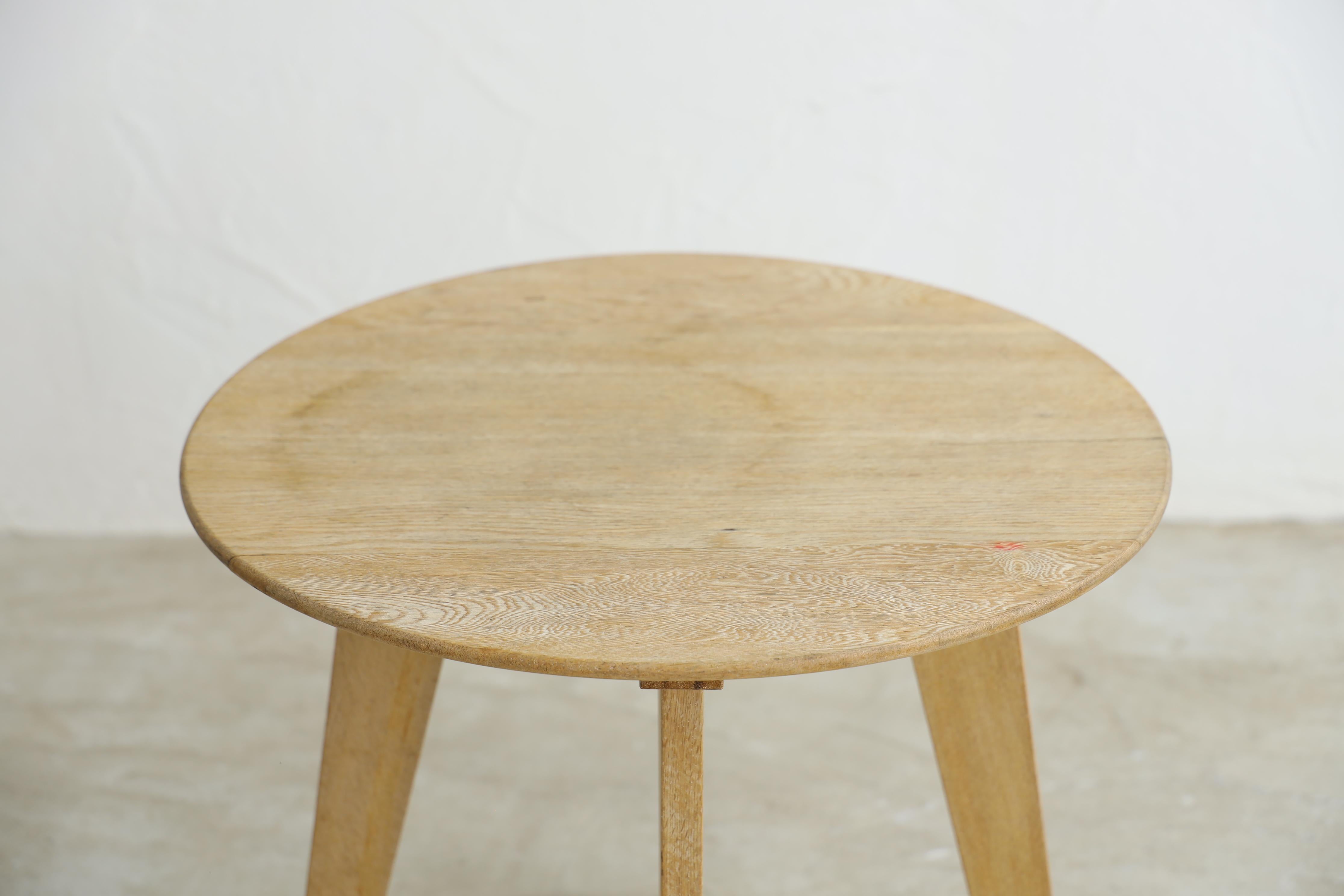 This is a compact round table that flares out at the end.

It has tapered legs that become thinner towards the base, giving it a delicate and elegant appearance despite its neat, unadorned construction.

The light color of the oak wood goes well