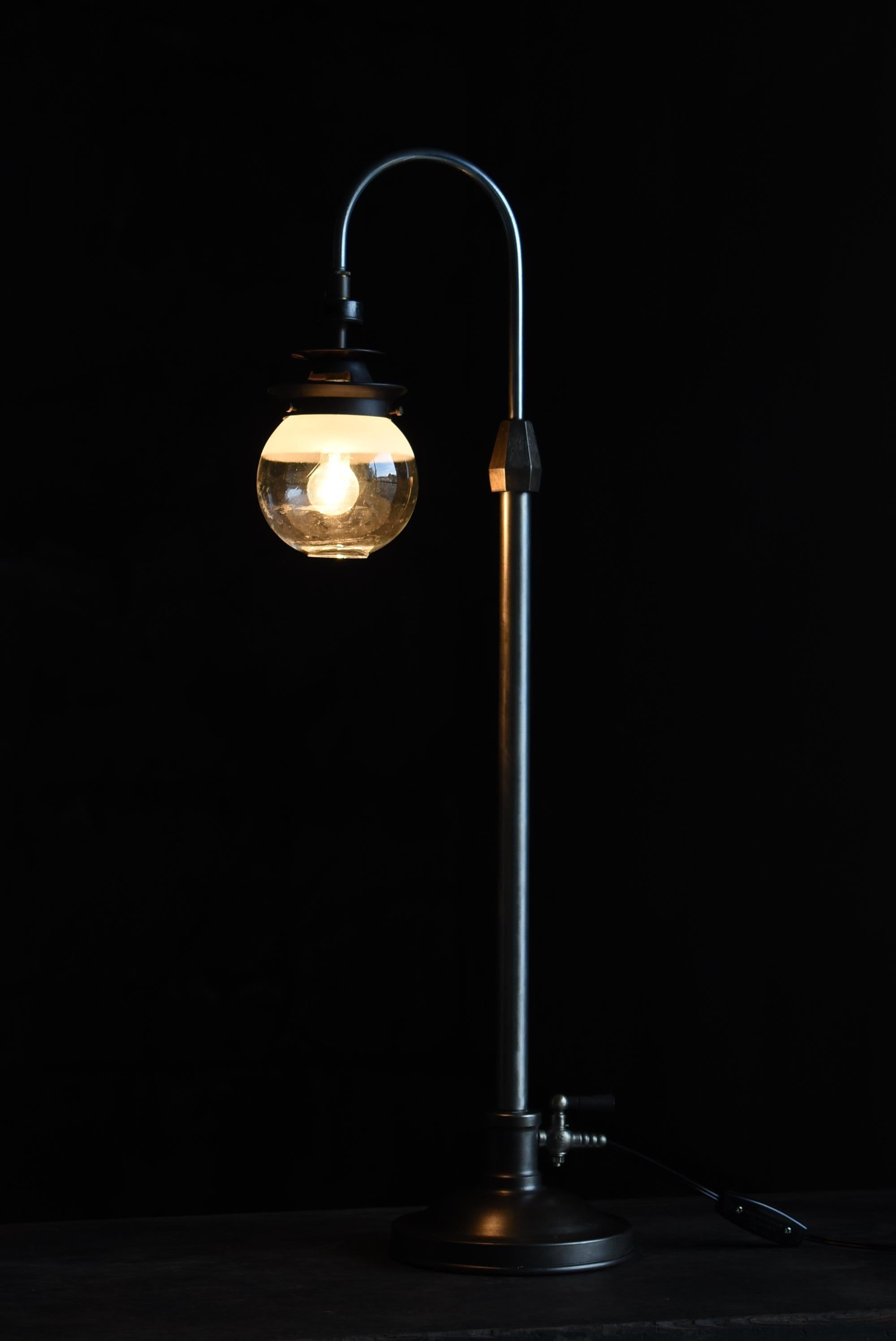 Il s'agit d'une très ancienne lampe de table fabriquée au Japon.
Cette lampe date du début de la période Showa (années 1920-1940).
Il est fabriqué en fer et en laiton.
L'abat-jour est en verre.

Le design/One est très moderne.
Elle est fabriquée de