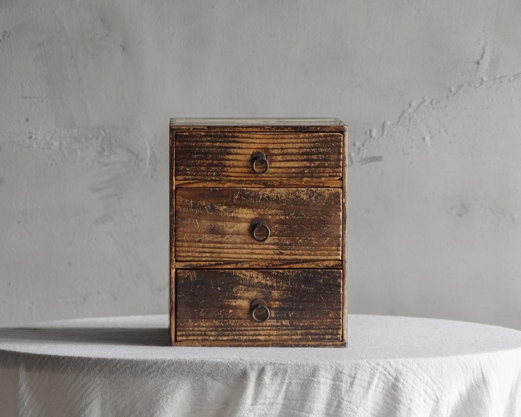 Cette boîte à tiroirs antique a été fabriquée à l'époque Taisho (1912-1926).

Boîte ancienne à trois tiroirs.
La texture distinctive et la présence tranquille cultivée au fil du temps sont les charmes déterminants de cette pièce.
Sa taille compacte