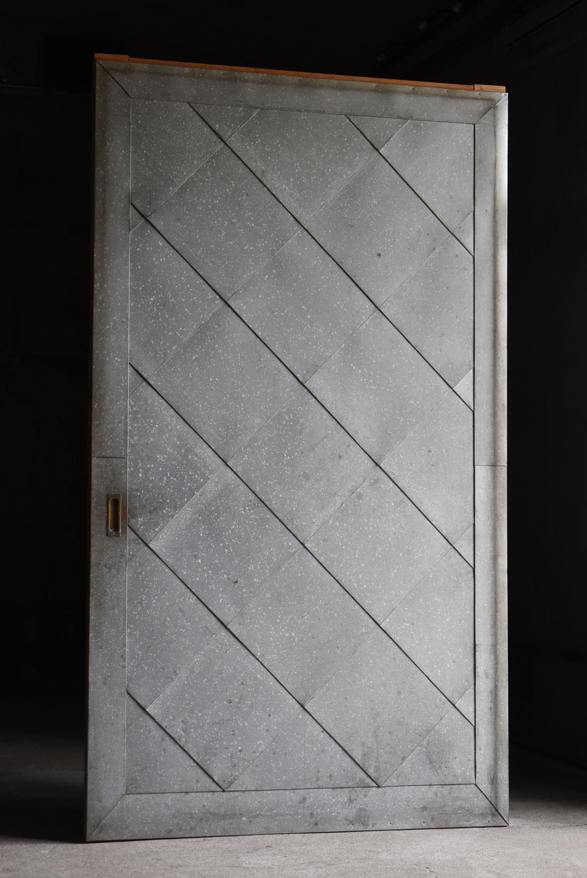This is an old Japanese sliding door covered with corrugated tin.
It was crafted sometime between the Meiji and Taisho periods (1860s–1920s), and such architectural fixtures have become increasingly rare in modern times.

The wooden frame is made of