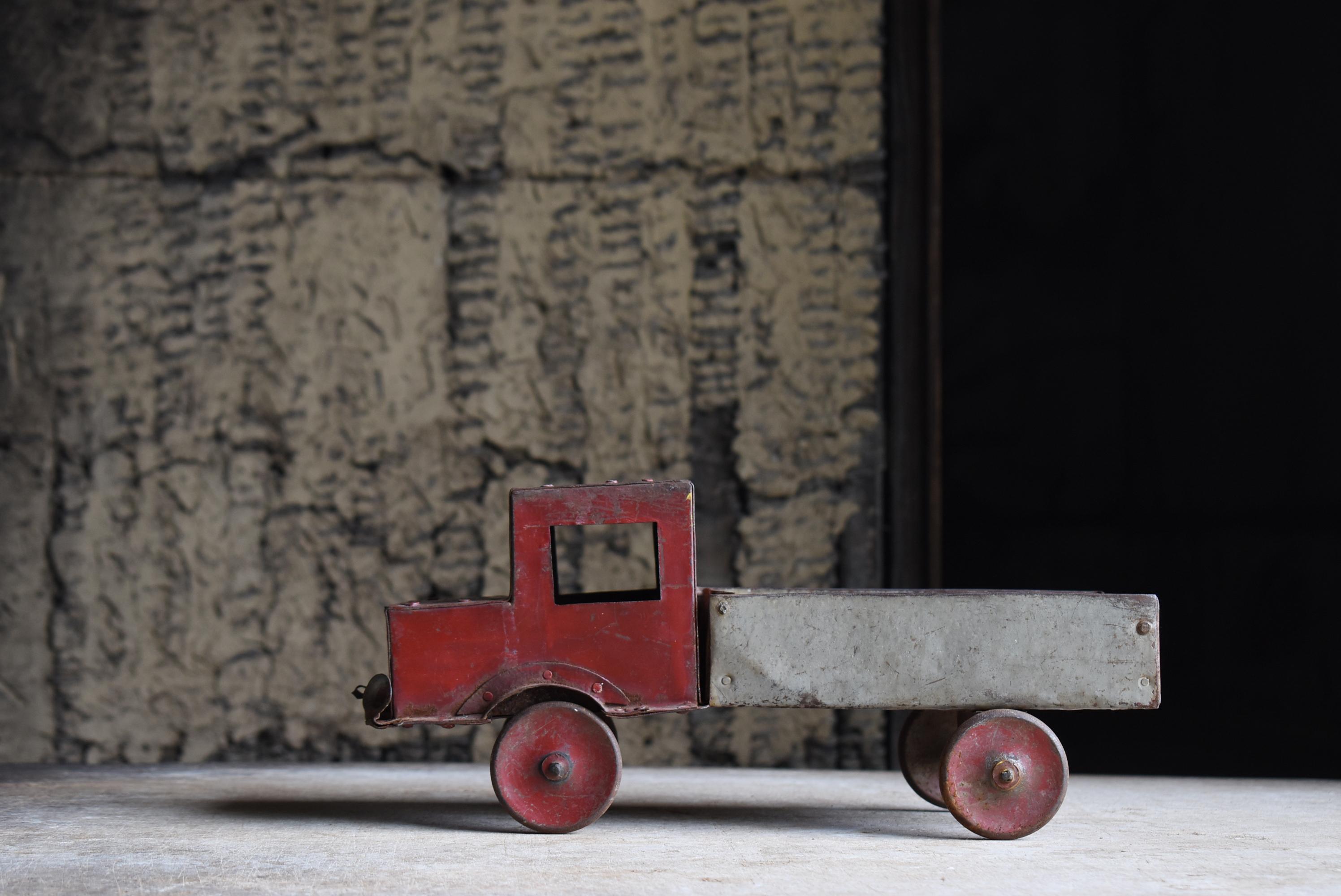This is an old tin toy truck made in Japan, believed to date back to the early Showa period (1920s–1940s). It is a rare artifact that speaks to the honest and humble craftsmanship of its time.

The truck features a simple color scheme of red and