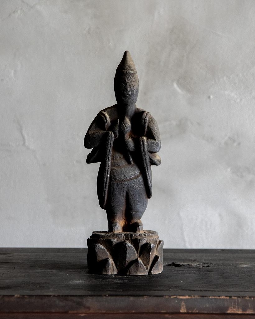 Cette ancienne figure bouddhiste en bois a été fabriquée pendant la période Edo (1603-1868).

Bien que l'identité spécifique de la divinité qu'elle représente soit inconnue, la figure a une présence douce et une aura calme et apaisante. Sa posture
