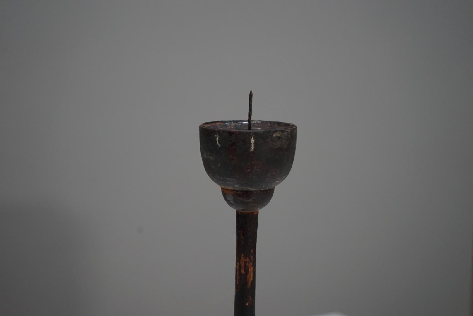 A Japanese antique wooden candle stand dating to the late 1800s.
The wood species is unknown, yet the material has aged into a deep, nearly blackened tone, conveying a strong sense of time and quiet dignity.
Its surface bears the soft wear of long