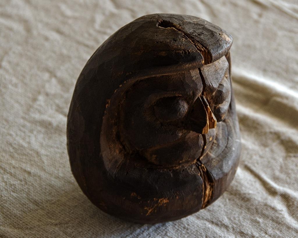 Este daruma antiguo se fabricó en la Era Edo tardía (1603-1868). 

Hecha de madera, desprende un encanto sencillo pero único que refleja la esencia cultural de su época. La textura natural de la madera está bellamente resaltada, con una pátina