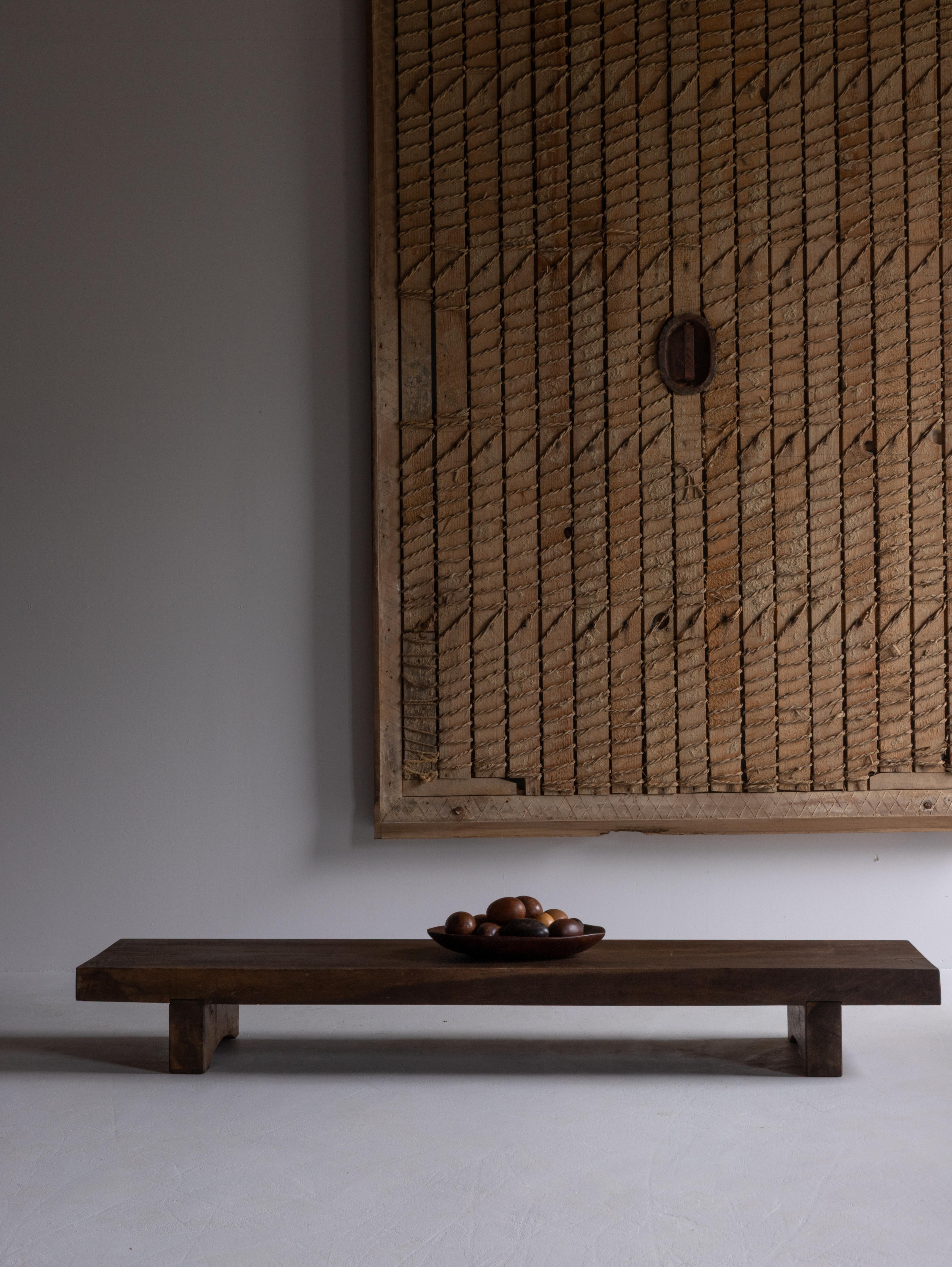 Table basse japonaise en bois à la présence discrètement captivante.
Conçue à l'origine comme un établi pour la coupe des tissus dans les maisons traditionnelles, cette pièce porte aujourd'hui la poésie sereine du temps.

Sa surface révèle de