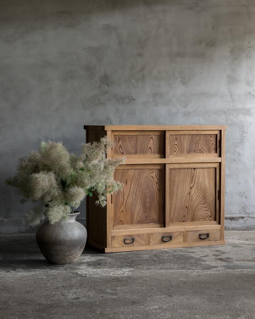 This antique wooden sliding door cabinet was crafted in the Taisho Era(1912-1926).

This cabinet features a stunning front made from Japanese Keyaki wood, known for its striking grain pattern that adds a visual richness to the piece. The doors