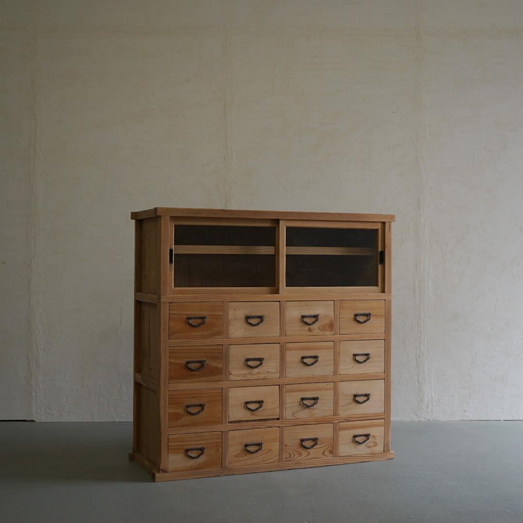 This is an old Japanese drawer storage shelf.
This is made of cedar wood.
This is a shelf with glass doors above the drawers.

There are 16 drawers in total, so you can store a lot of things.
All 16 iron handles are present and in good