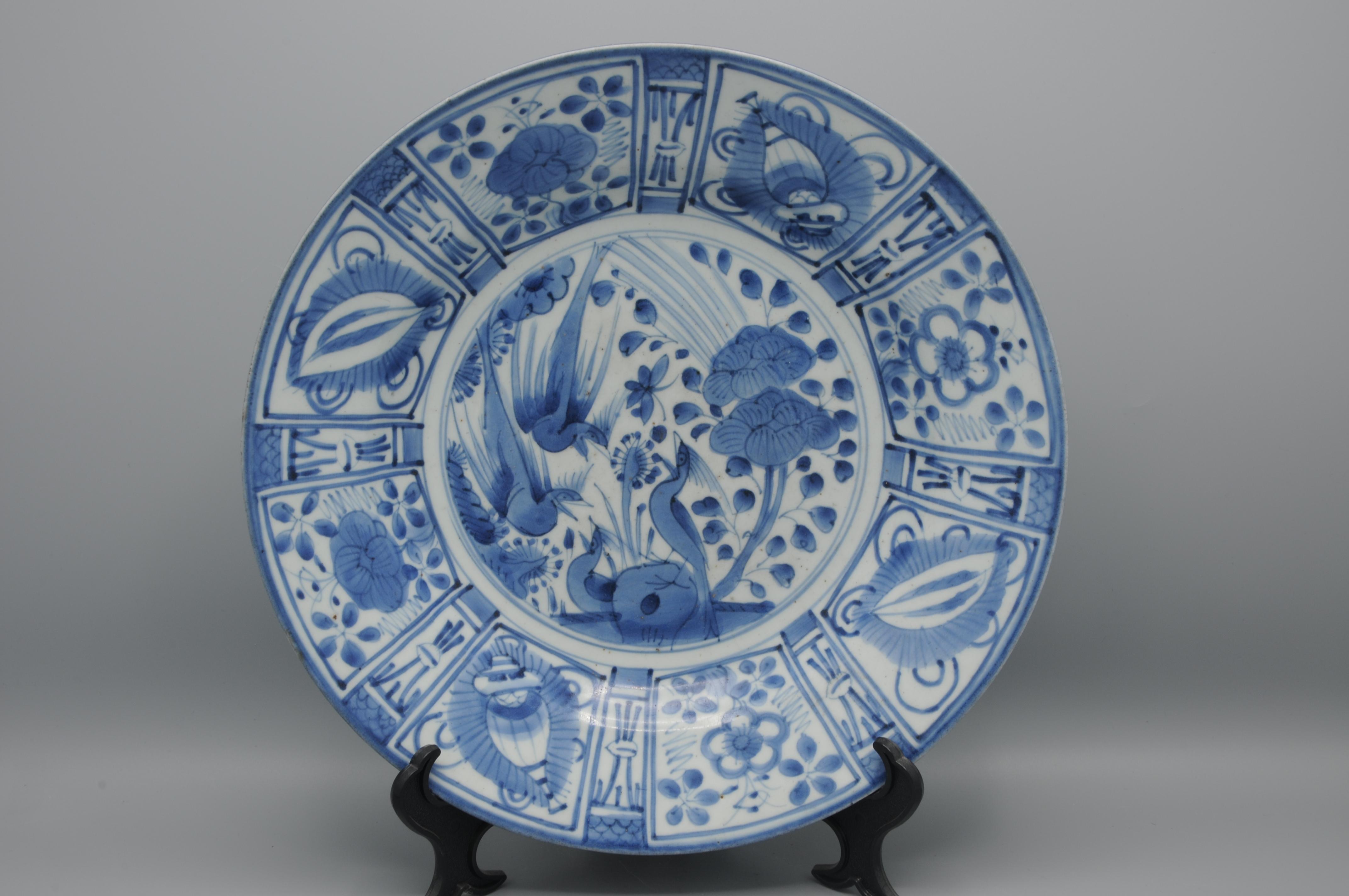 Plato de Porcelana Azul y Blanca Japonesa del Siglo XVII Estilo Kraak, Hornos de Arita 1670 - 1700. 
El diseño central muestra tres faisanes, uno posado en una roca entre peonías en flor y dos volando por encima. Los laterales y el borde, de estilo