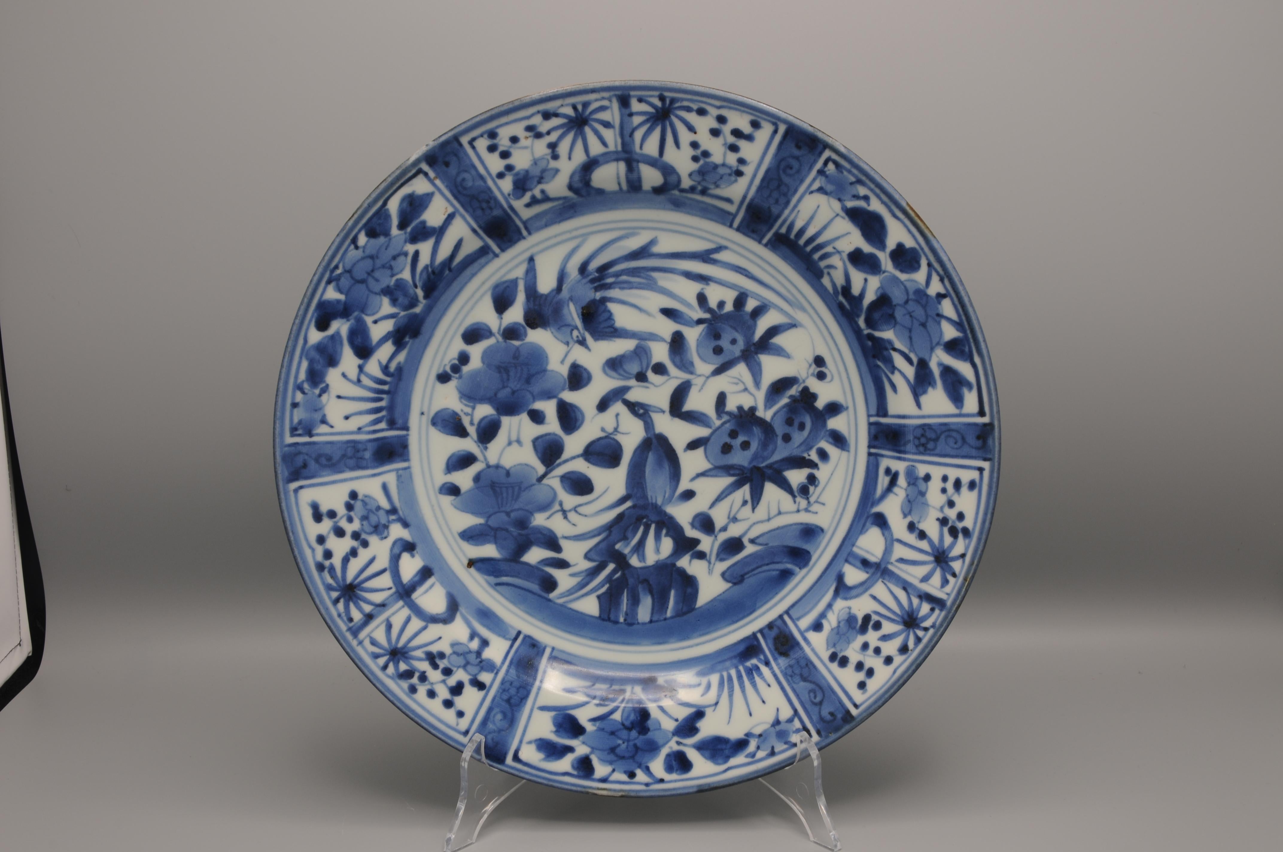 A 17th Century Japanese Blue and White Porcelain Dish in the Kraak Style, Arita Kilns 1670 – 1700. 
Decorated in underglaze blue with two phoenixes with pomegranate and camellia enclosed by a double concentric band. The sides and rim in Chinese