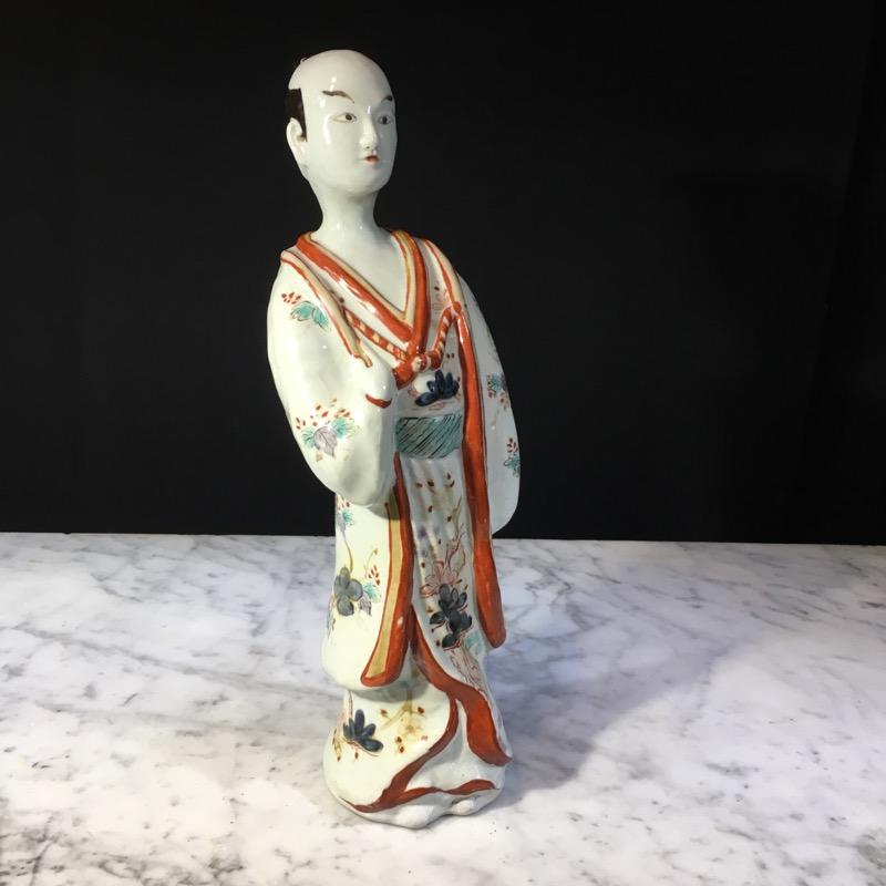 Large Rare Japanese Arita porcelain figure of an actor, modelled standing in an alert manner with a quizzical expression, dressed in flowing robes with multi-layers each decorated in Imari colors of iron red underglaze blue, pale purple and watery