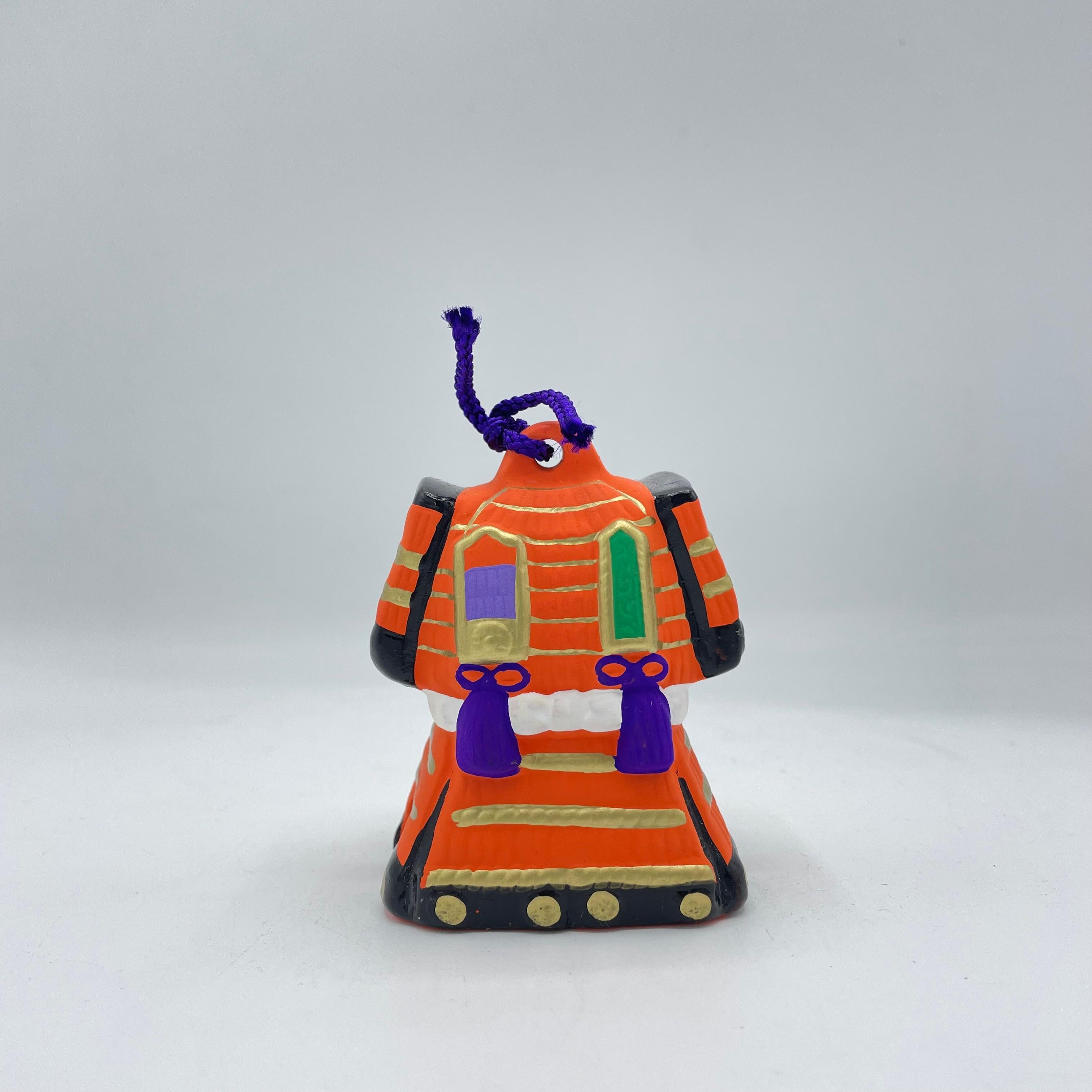 A Yoroi Dorei is a traditional Japanese clay bell shaped like a suit of samurai armor. These bells are often handcrafted and painted with intricate detail, symbolizing strength, protection, and bravery. Originally used as charms or decorative items,