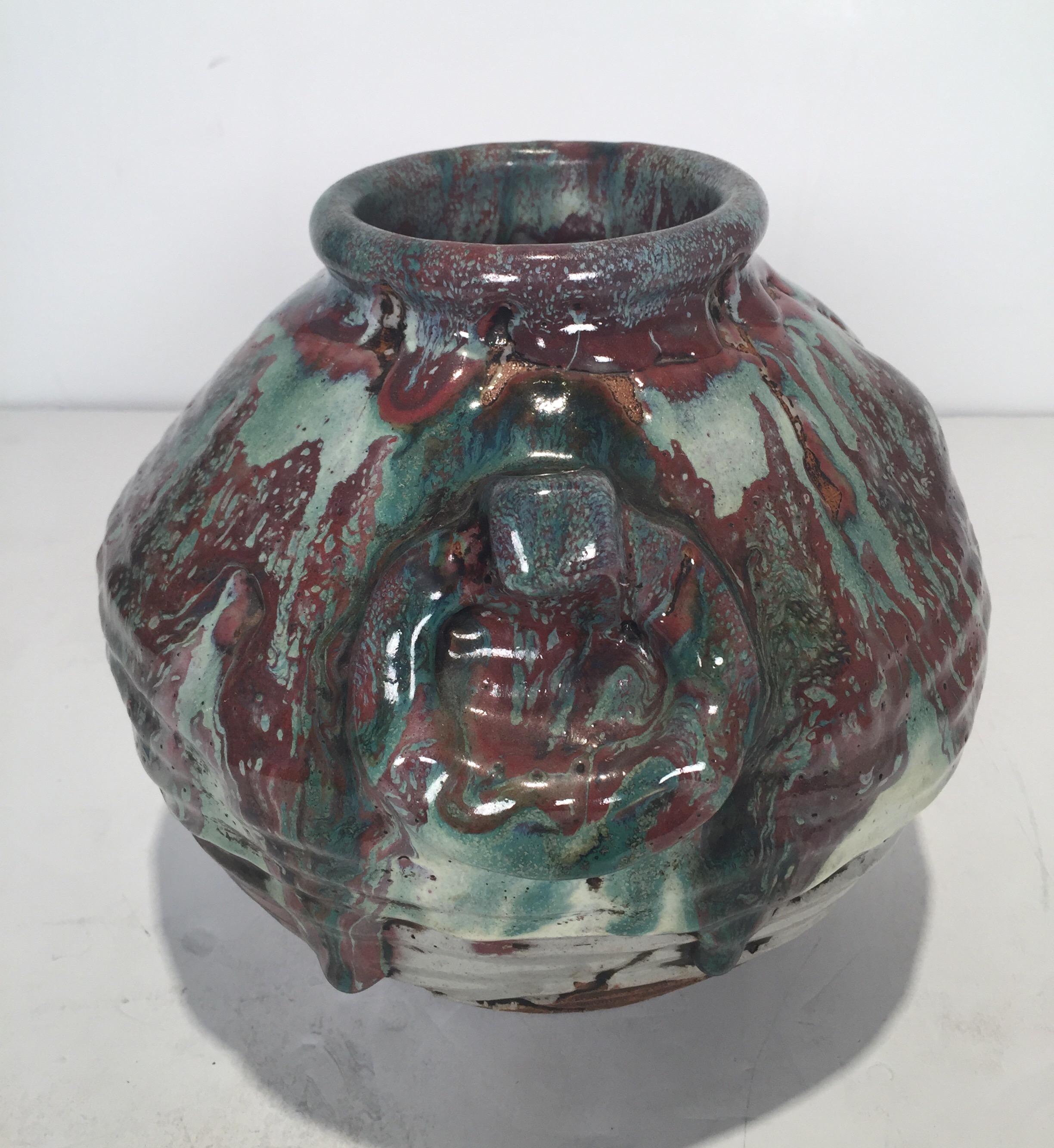 Early 20th century art pottery vase with a multicolored glaze. The bulbous body with molded ring handles and hick colored glaze with dripped design.