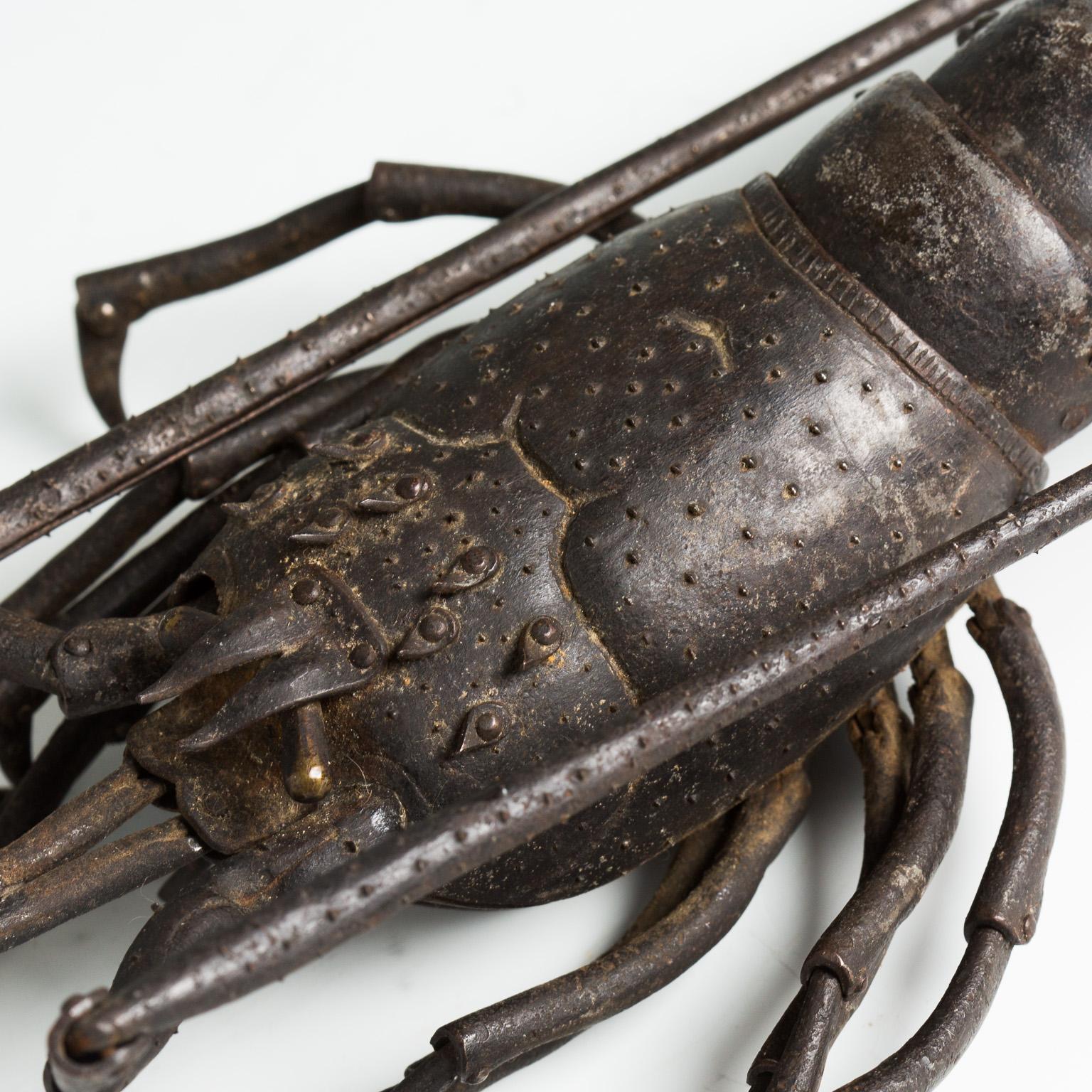Cet okimono articulé représente un homard au rendu naturel, avec des membres, des antennes, un corps et une queue entièrement articulés. Il est livré avec une boîte de rangement en bois portant une inscription.
Signé : Myochin Muneharu saku.
 
