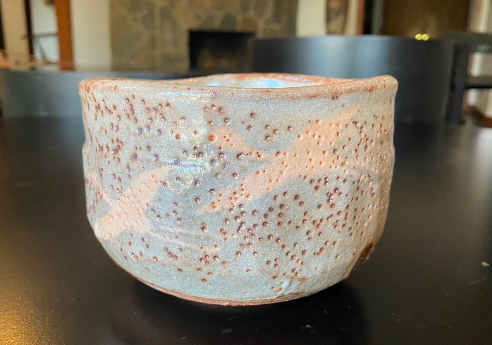 A beautiful Japanese Mingei Nezumi Shino Ware (志野焼, Shino-Yaki) pottery Chawan tea bowl for tea ceremony that features a sumptuous glaze with wonderful subtle shifts in color, pattern, and texture and a quite wonderful bird/crane (Tsuru (鶴))