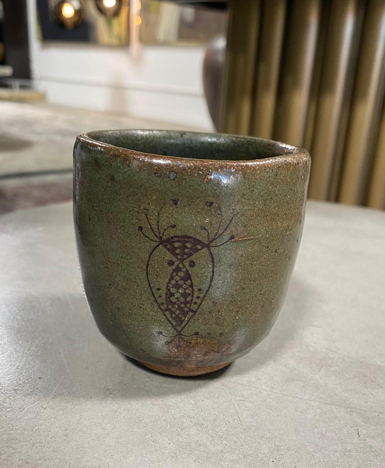 Magnifique tasse à thé yunomi japonaise, à la glaçure foncée, sur laquelle est peinte la silhouette d'une créature caractéristique de l'artisan.

Cette œuvre (ainsi qu'un deuxième yunomi - clairement du même artiste. Veuillez voir la dernière