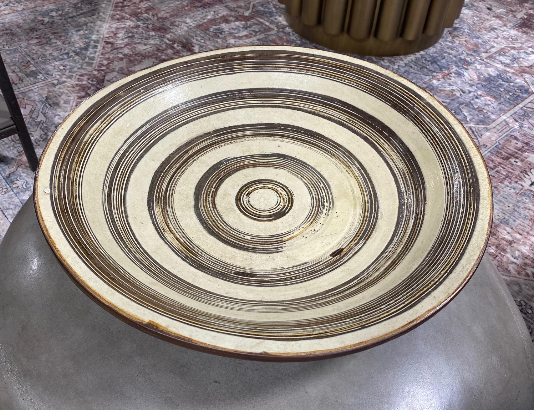 A truly magnificent in size and execution Japanese stoneware studio pottery charger/bowl. This exceptionally large and heavy asymmetrical work features a circular swirl design pattern and has a very over undulating rim-flow design. 

This