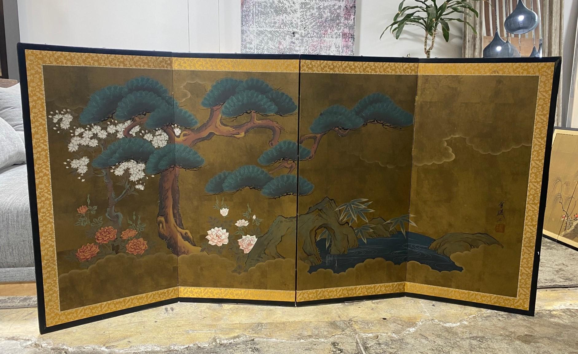 A gorgeous hand-painted four-panel Japanese/Asian Byobu folding screen depicting a nature landscape scene with blooming/ blossoming flowers and a venerable pine tree with limbs stretching out over a flowing river/lake. The deep, rich colors, gold