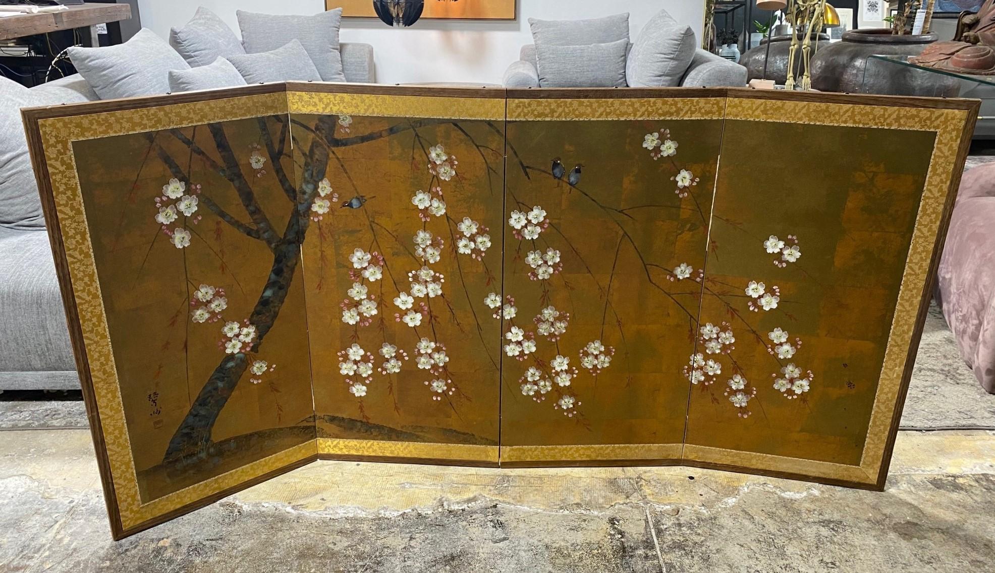 A gorgeous hand-painted four-panel Japanese Byobu folding screen depicting a blossoming cherry tree/ serene nature scene with playful birds amongst the blooming branches. The deep, rich colors, gold leaf, complex design/composition, and beautiful